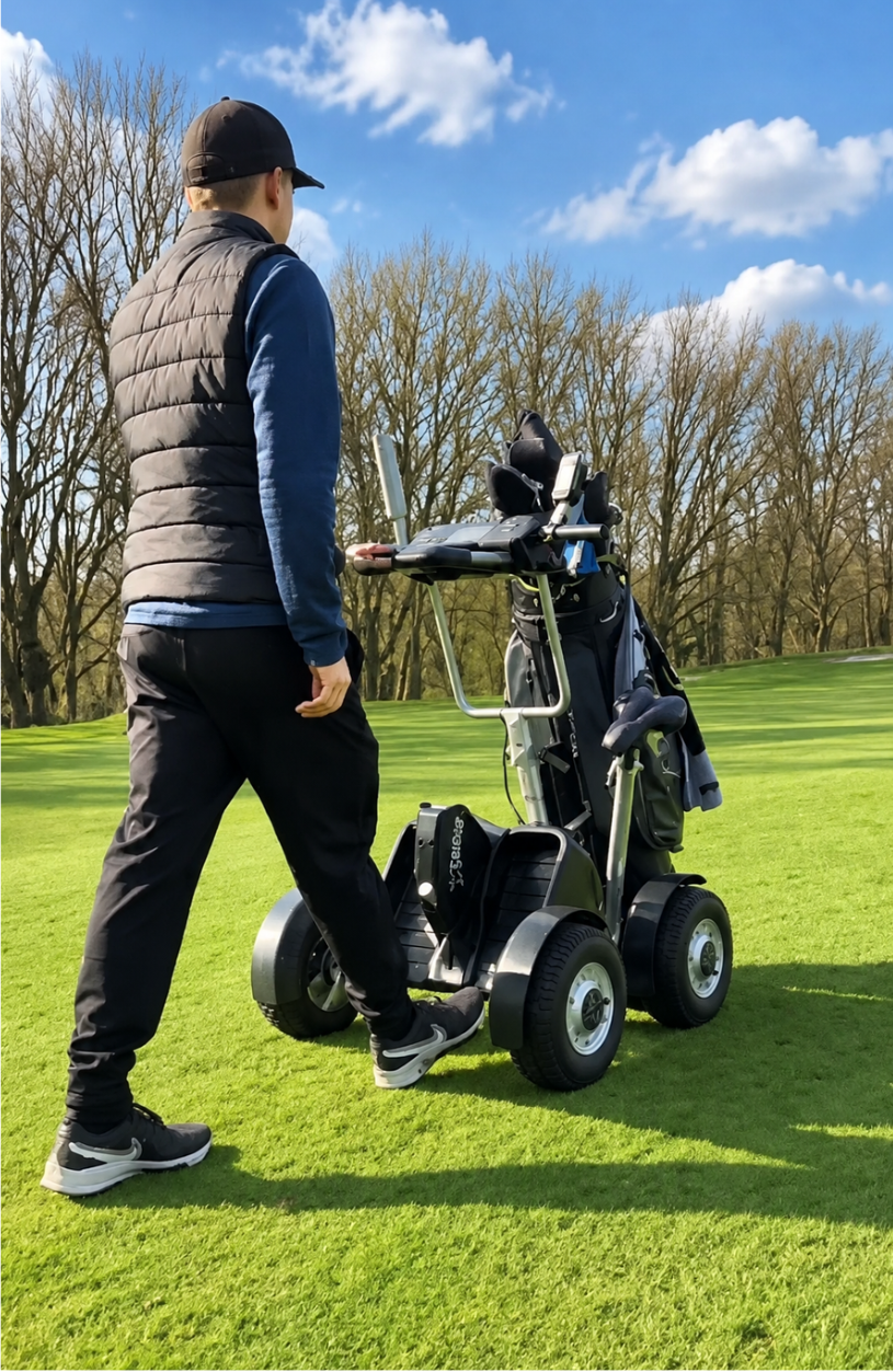 Man standing beside a four-wheel electric golf push cart carrying a golf bag on a sunny course