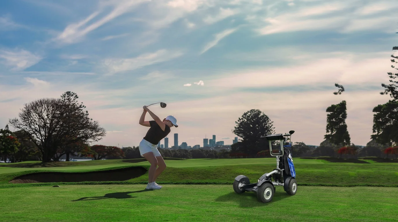 Golfer swinging a club on a sunny golf course beside a golf cart, with a city skyline in the background