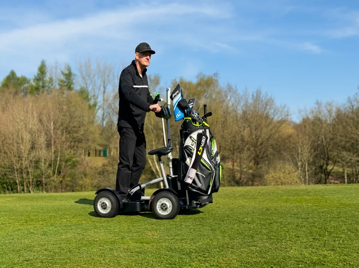 Golfer riding a black three-wheeled electric golf scooter with a golf bag on a grassy course