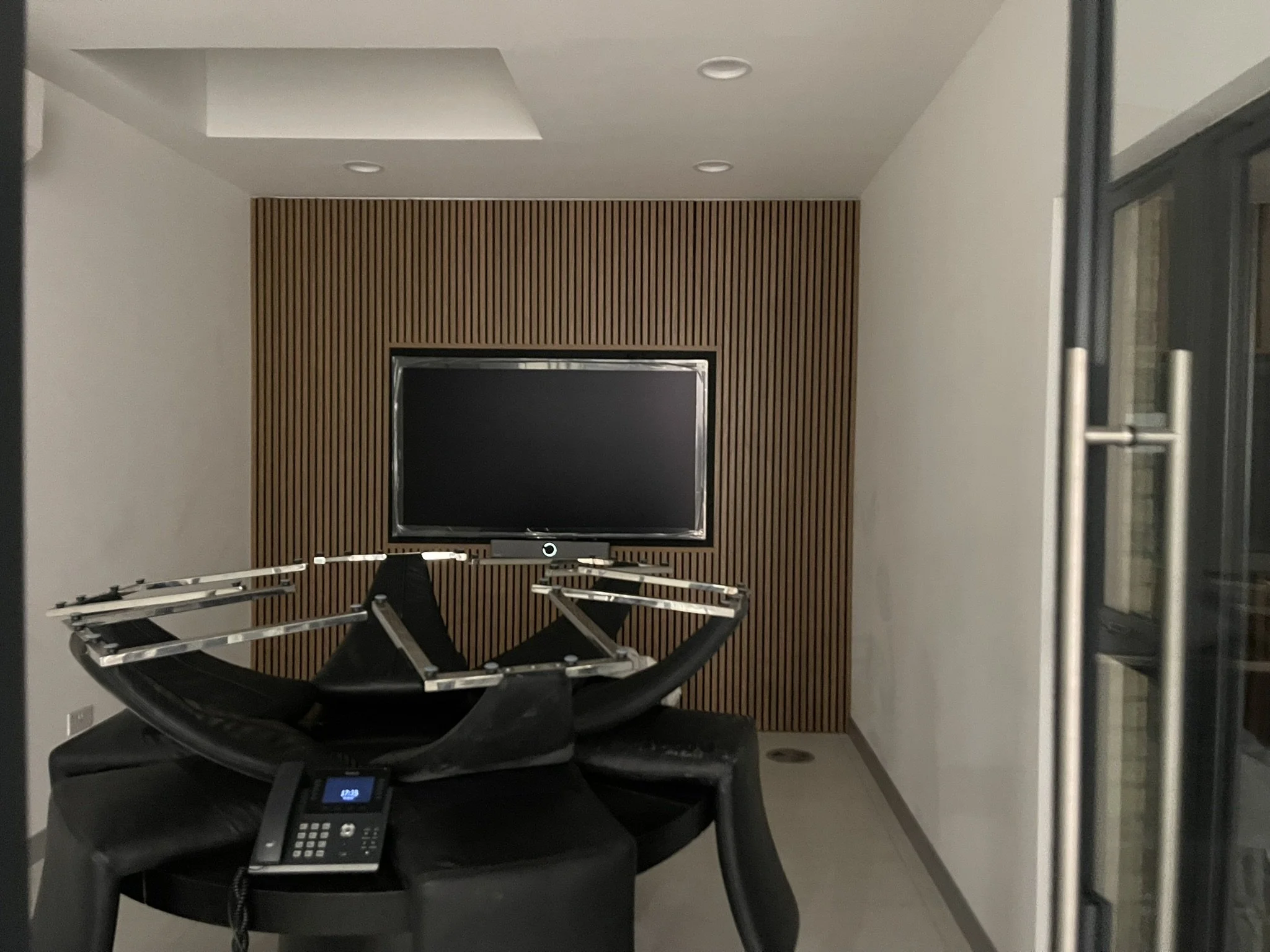 Modern home theater with a wall-mounted TV, wood slat accent wall, and black massage chair in the foreground