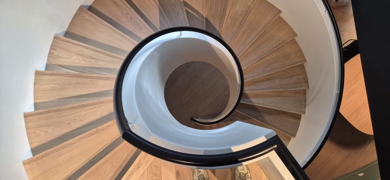Escalier hélicoïdal à marches en chêne et main courante en acier noir, vu de dessus, réalisé par Austral