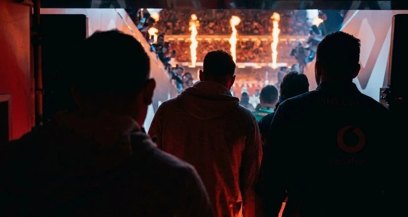 People watching a sports event or concert with pyrotechnics and flames on a large screen.