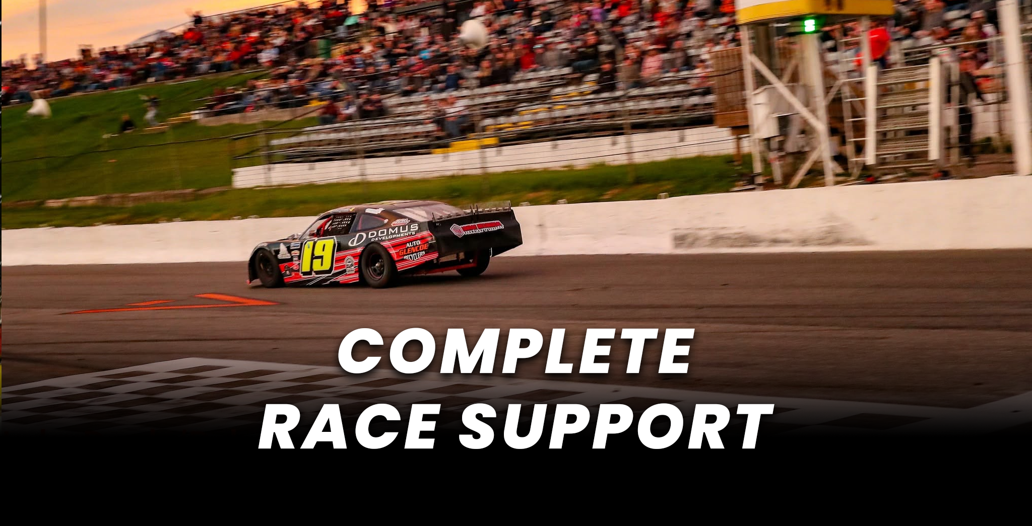 Race car number 19 speeding around a dirt track in front of a packed grandstand, with “Complete Race Support” text overlay.
