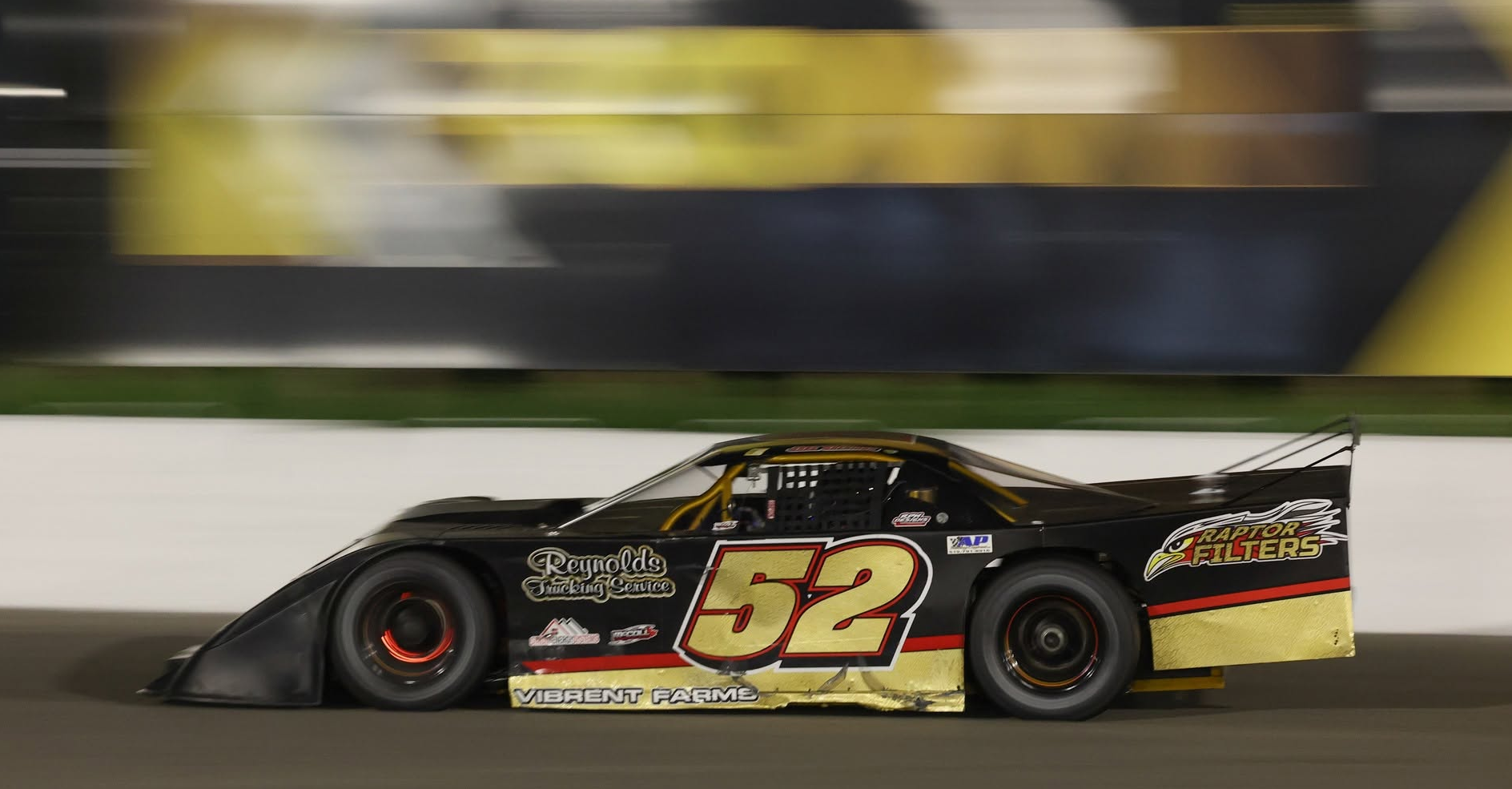 Black and gold No. 52 outlaw super late model race car speeding around a track