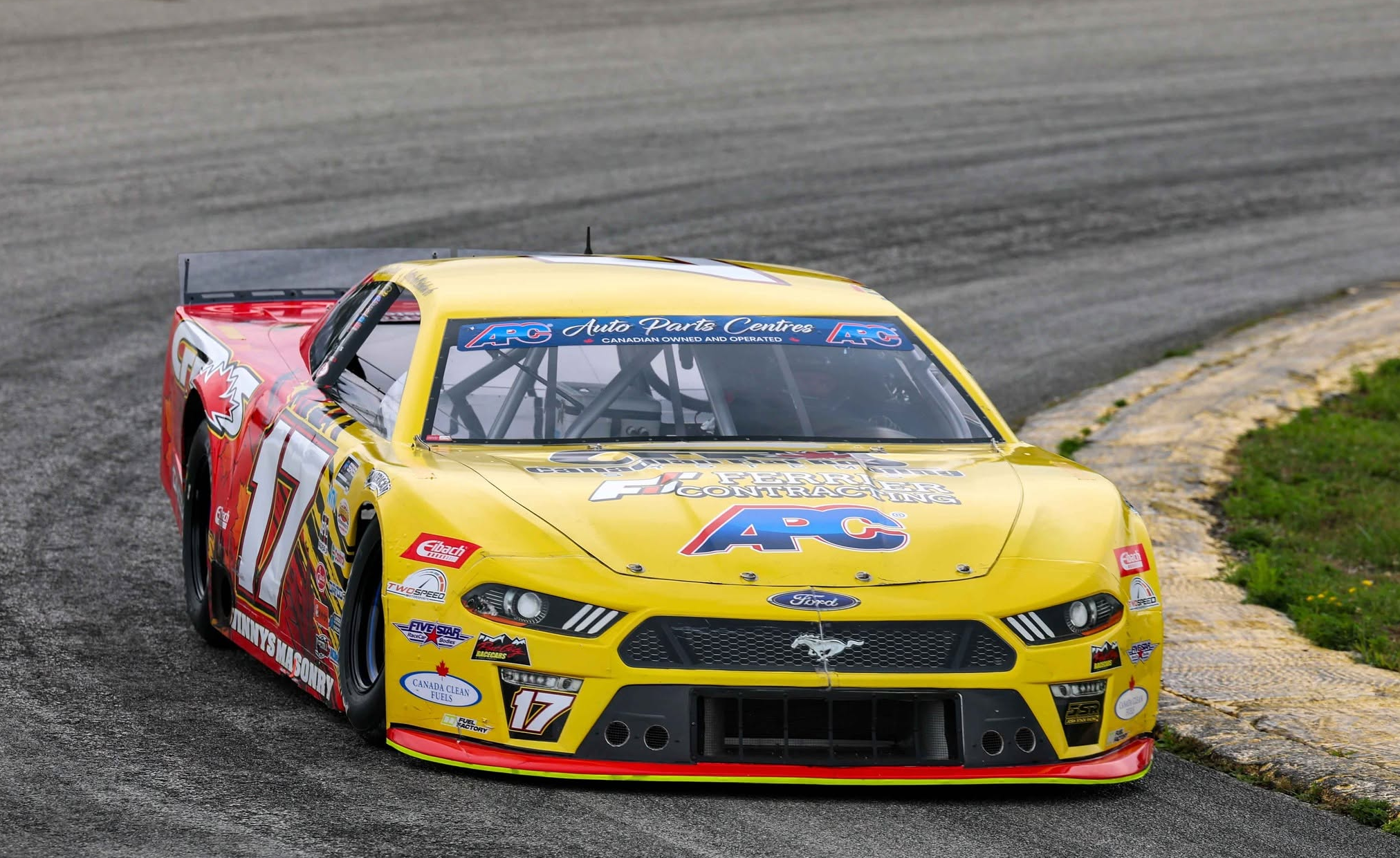 Yellow and red No. 17 Ford Mustang stock car on a paved racetrack