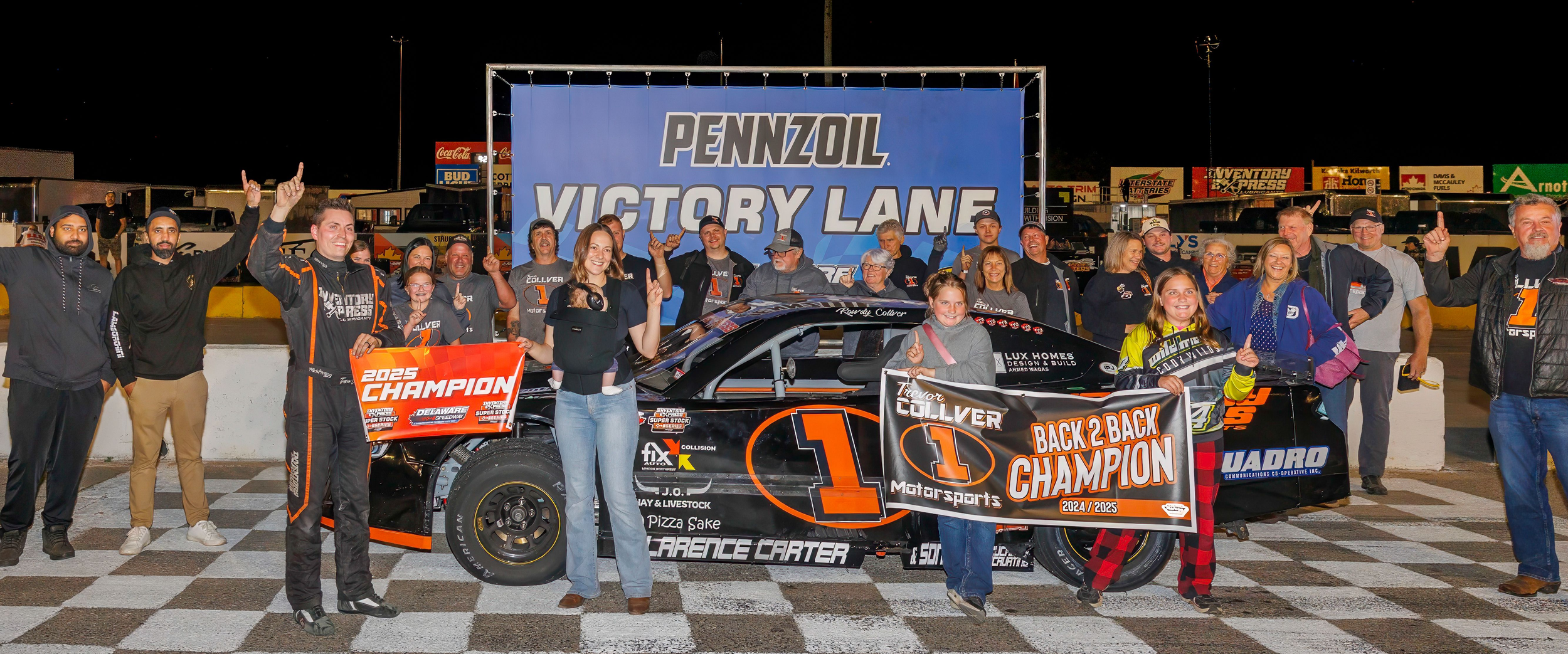 Race car driver and team celebrating a 2025 championship victory beside a No. 1 stock car on a victory lane podium