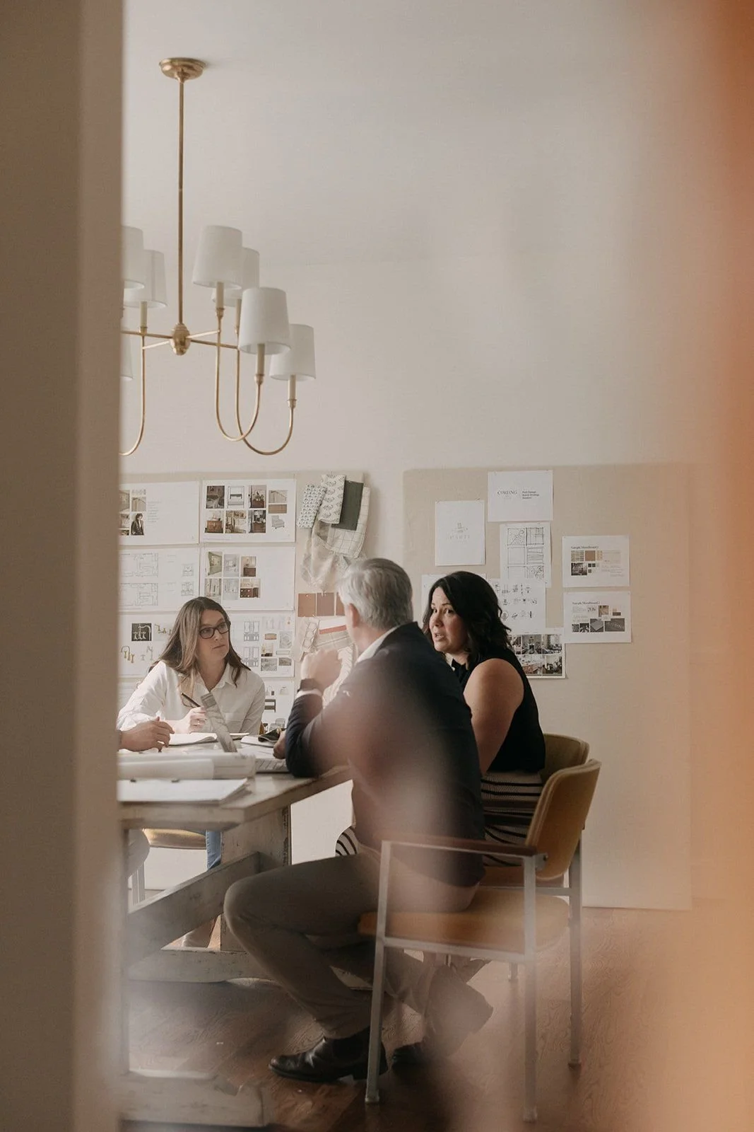 Three designers discussing plans around a table in an interior design studio.