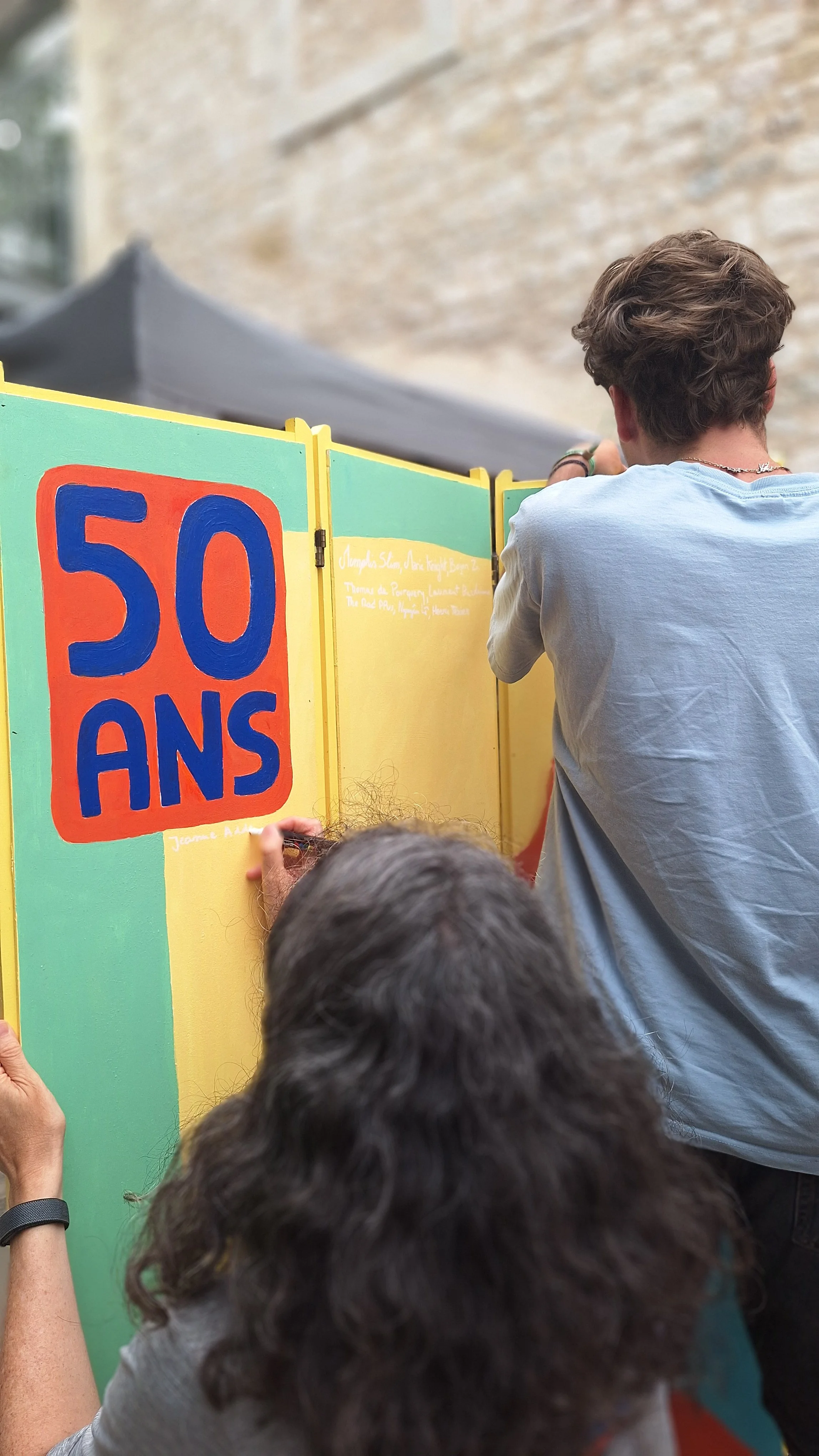 Personnes devant un stand coloré affichant une grande pancarte « 50 ANS ».