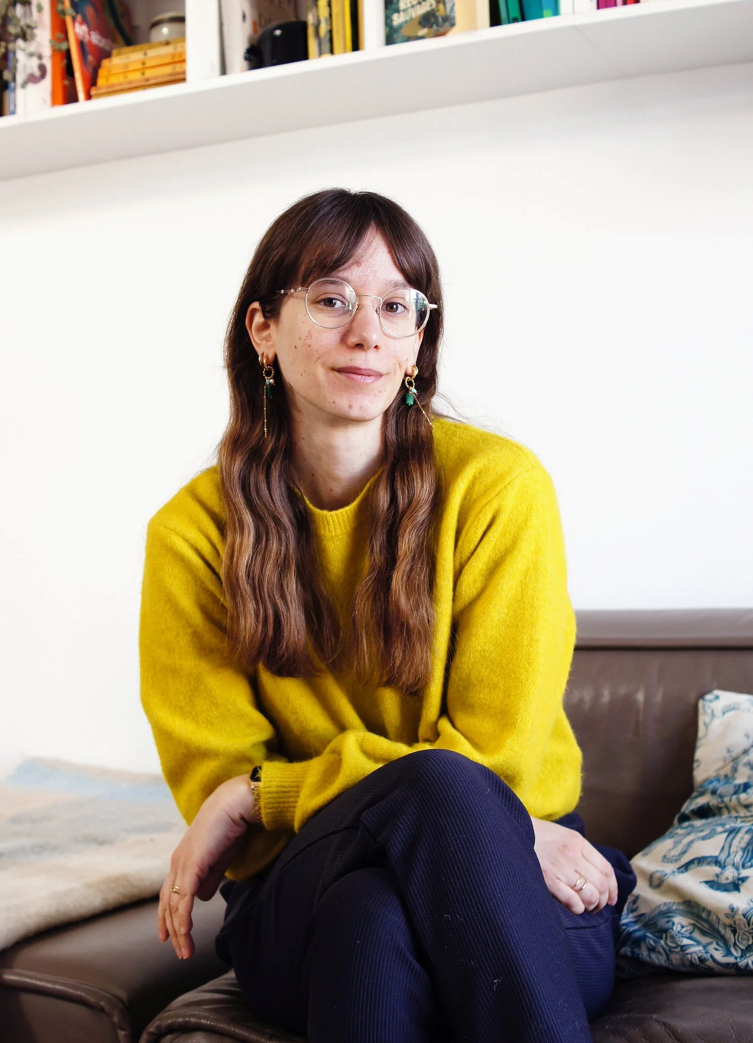 Photo portrait de moi avec un pull jaune, des cheveux longs, des lunettes et des boucles d'oreille