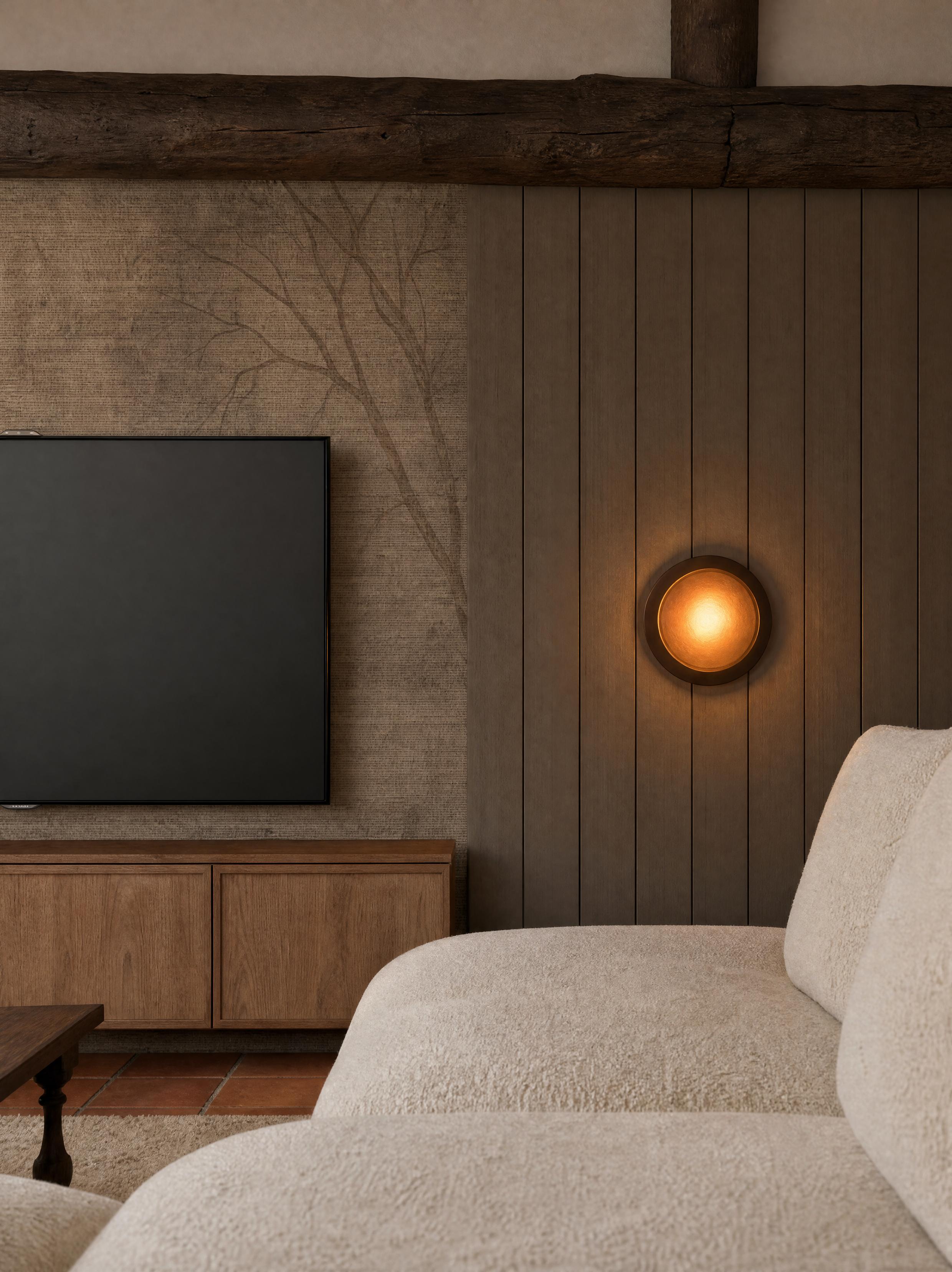 Vista de um canto de uma sala com parede de madeira vertical, luminária com luz âmbar, televisão em um móvel de madeira e parte de um sofá bege com almofada