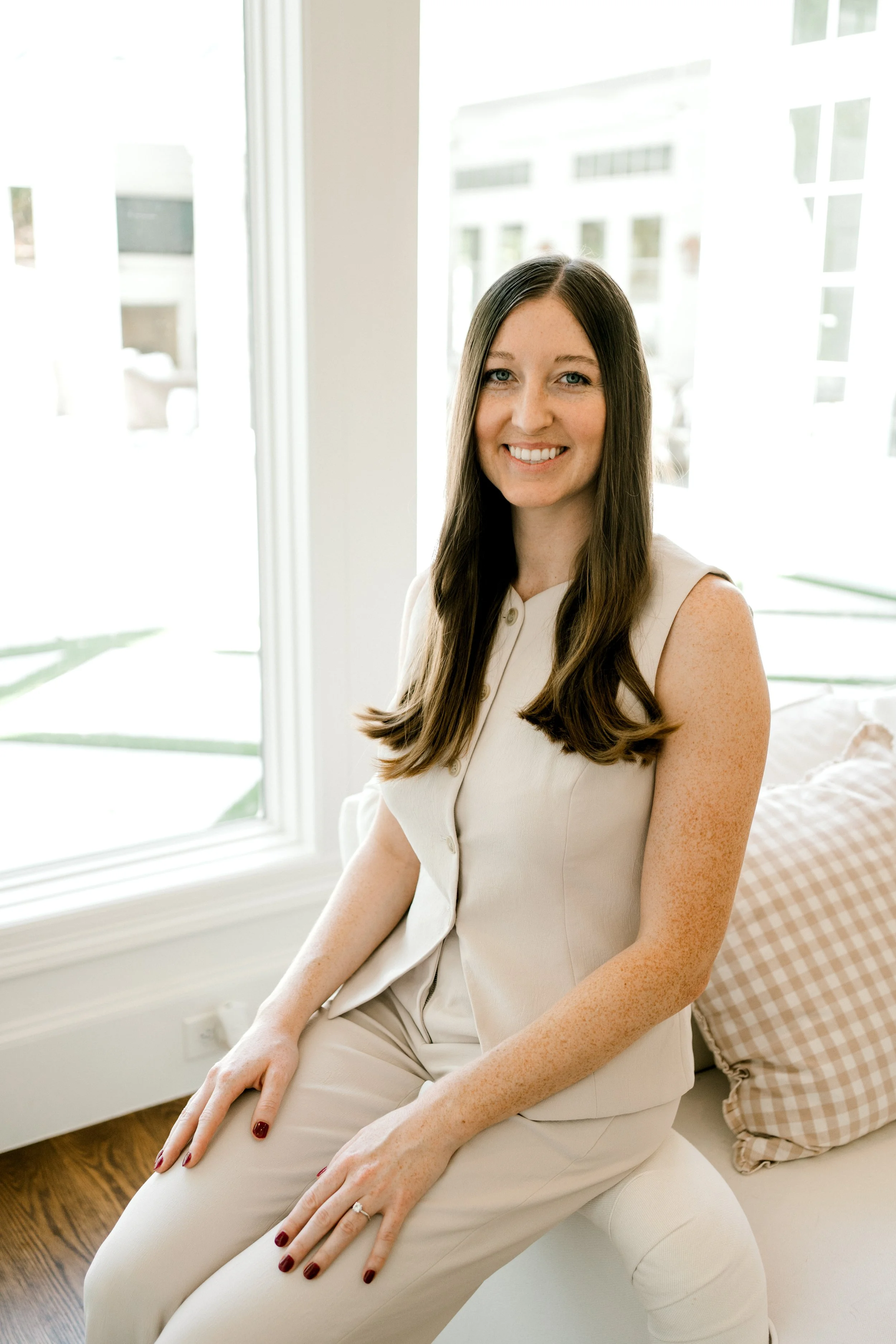 Amanda Polton, founder of OrganizePro, smiling while seated beside a bright window.