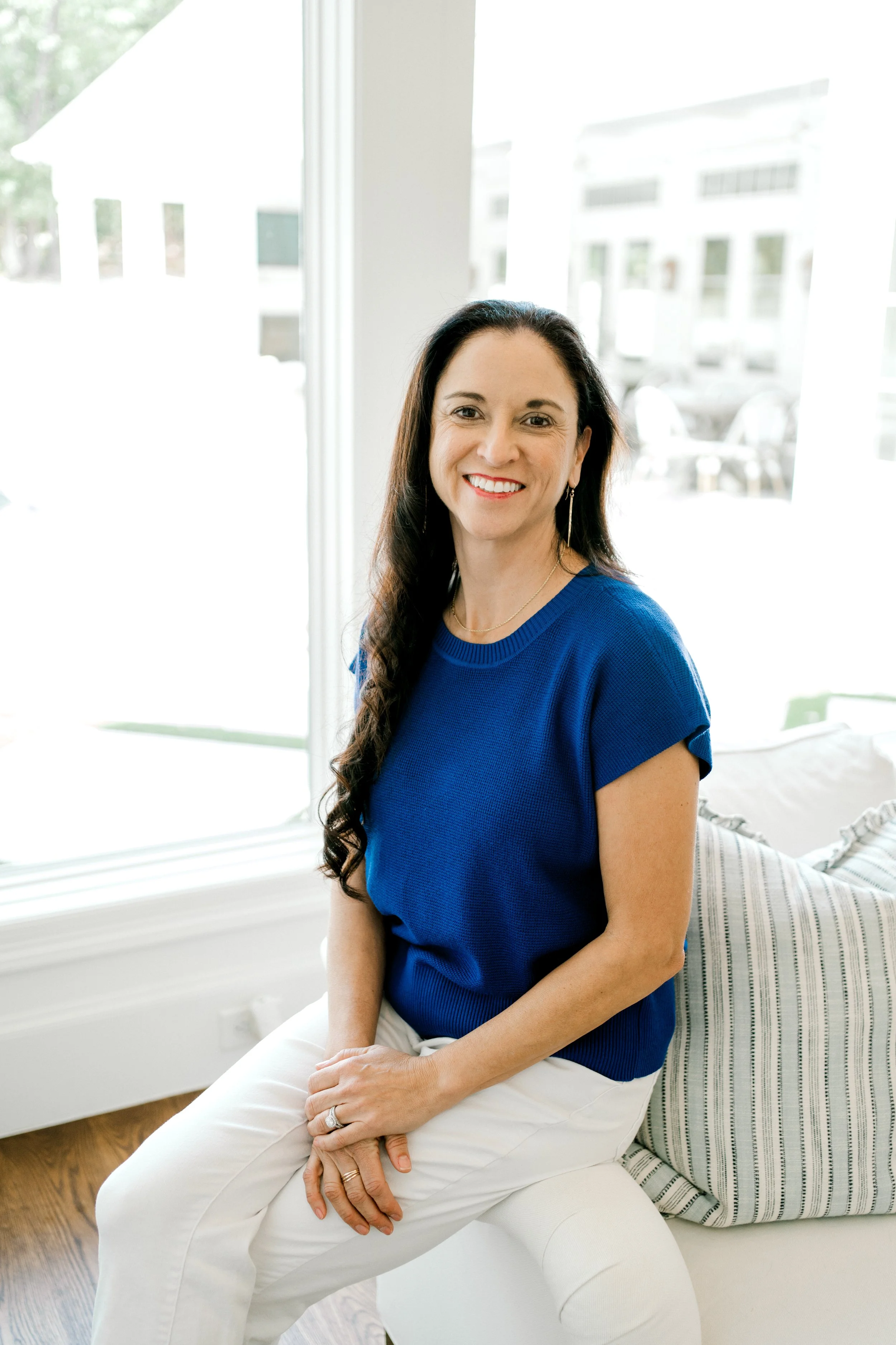 Amanda G., Lead Organizer at OrganizePro, smiling while seated beside a window in a blue blouse.
