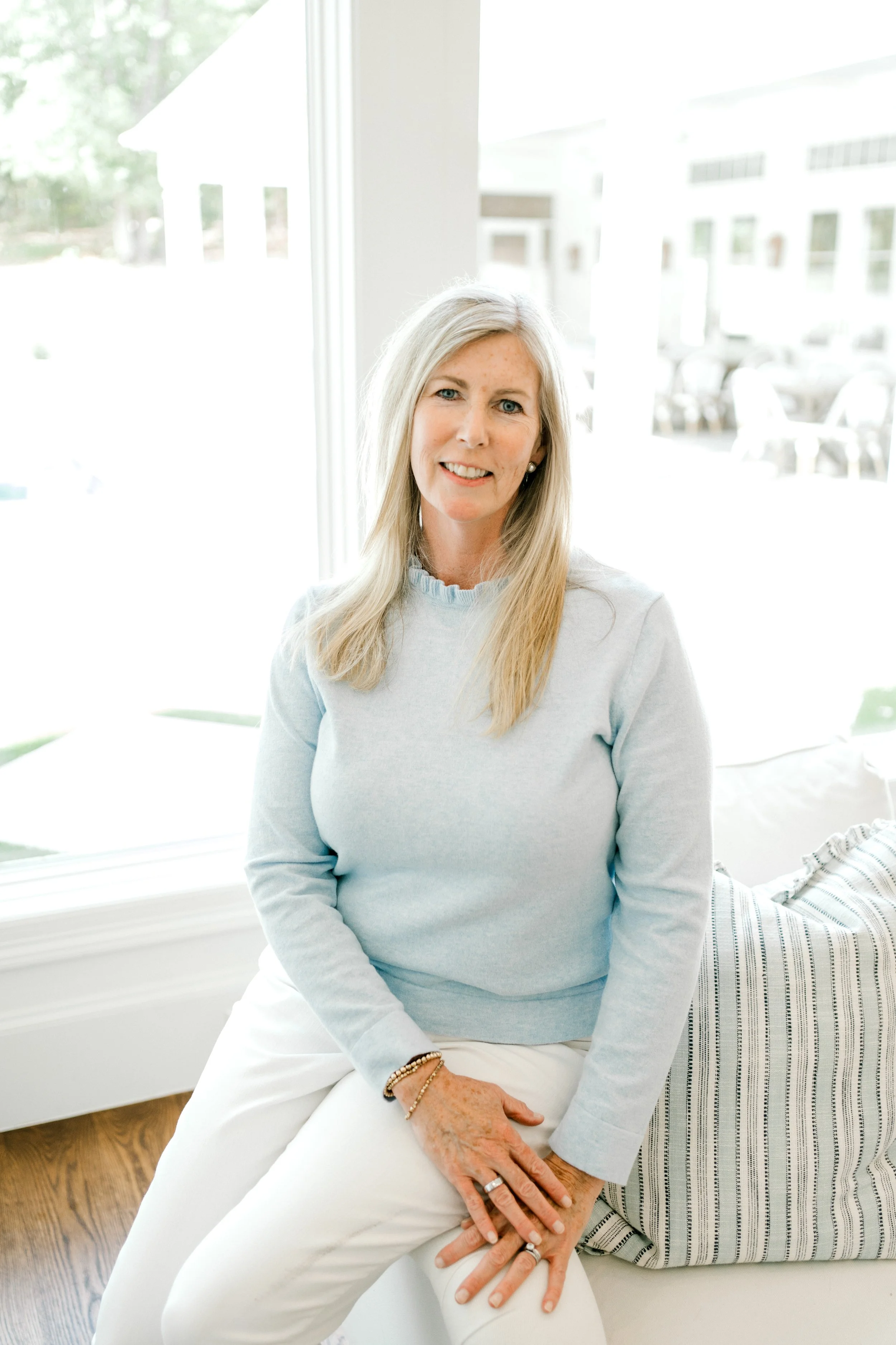 Lundy, Lead Organizer at OrganizePro, smiling while seated beside a bright window in a light blue sweater.
