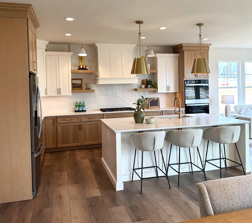 Bright, organized kitchen featuring white and natural wood cabinetry, a large island with seating, and clear countertops that make everyday household routines easier.