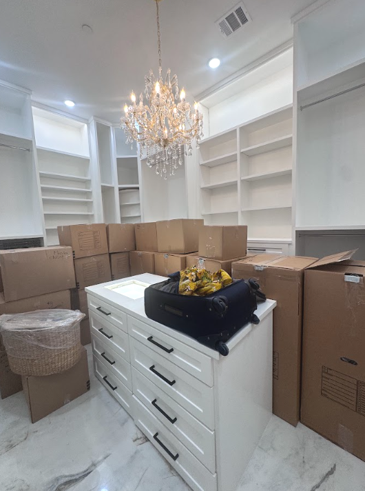 Large walk-in closet filled with moving boxes and unpacked belongings before professional unpacking and organizing.