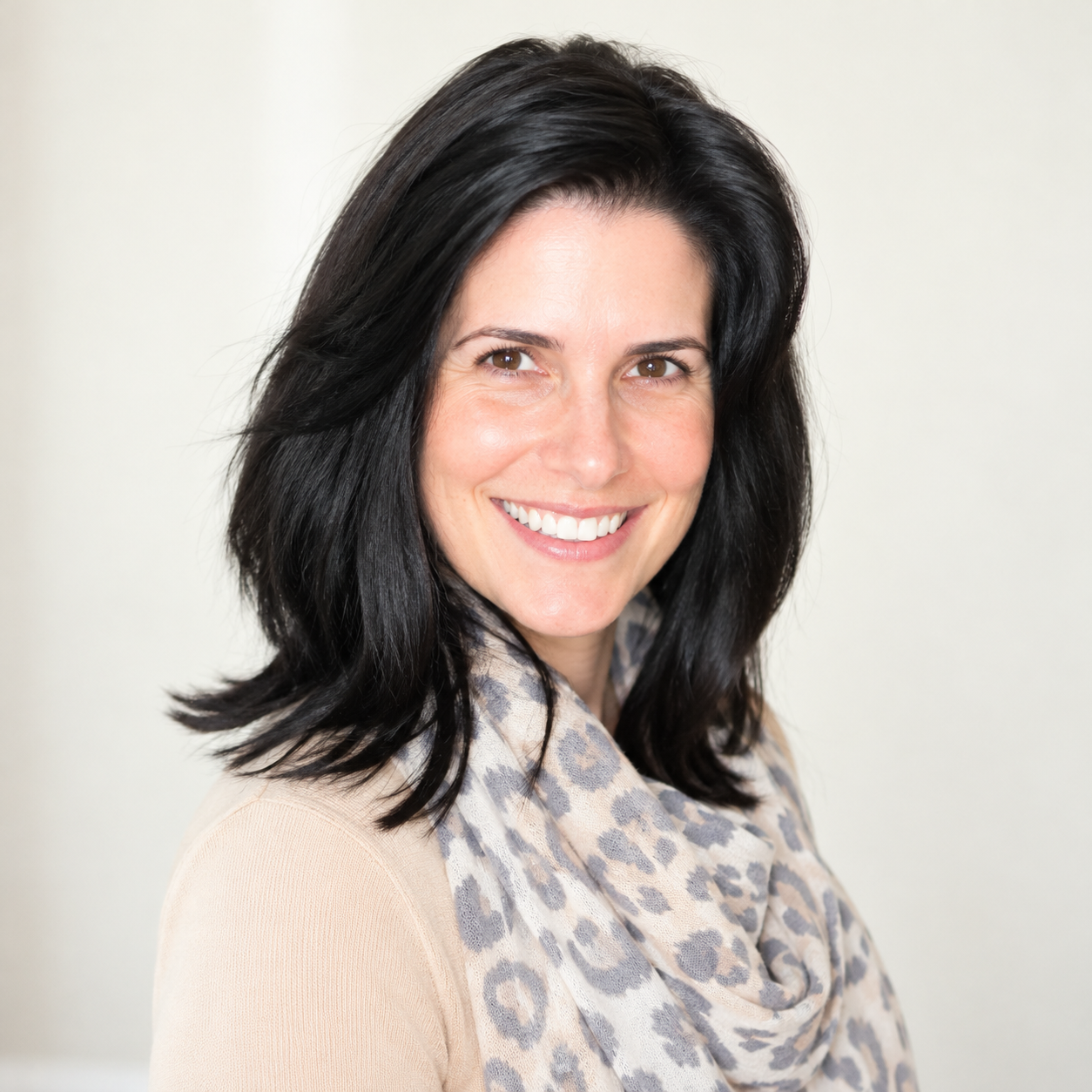 Julie, professional home organizer at OrganizePro, smiling in a beige top and patterned scarf for her team portrait.