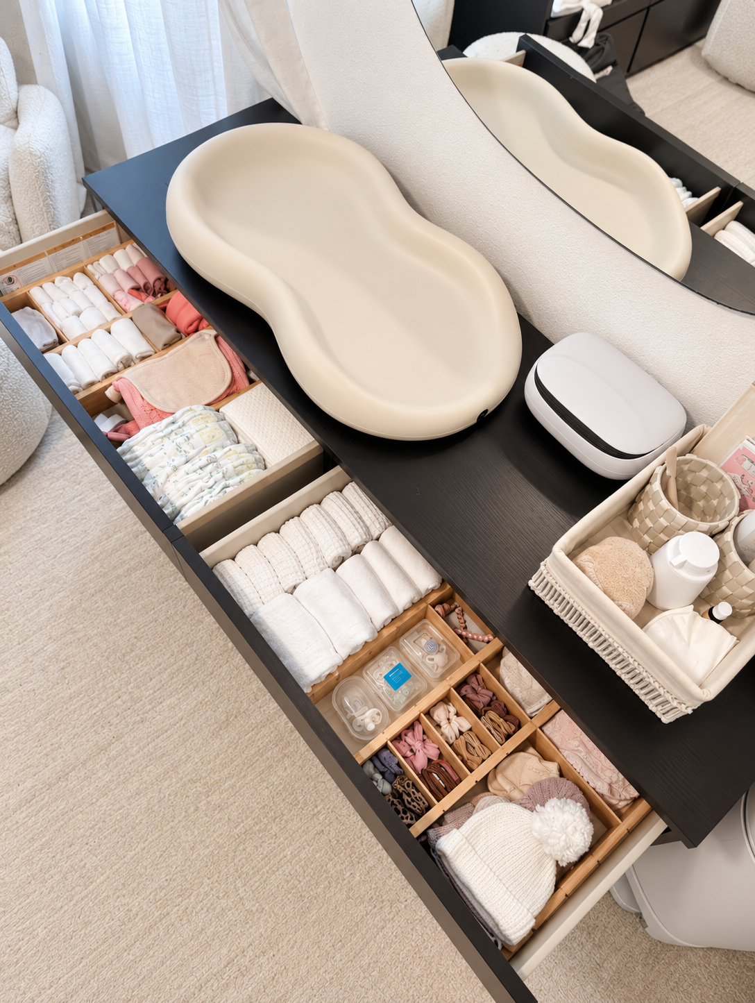Organized nursery dresser drawers featuring neatly folded baby clothes, diapers, and everyday essentials arranged in custom drawer dividers.