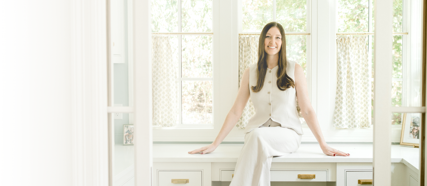 Founder, Amanda Polton, of OrganizePro smiling while sitting on a desk.