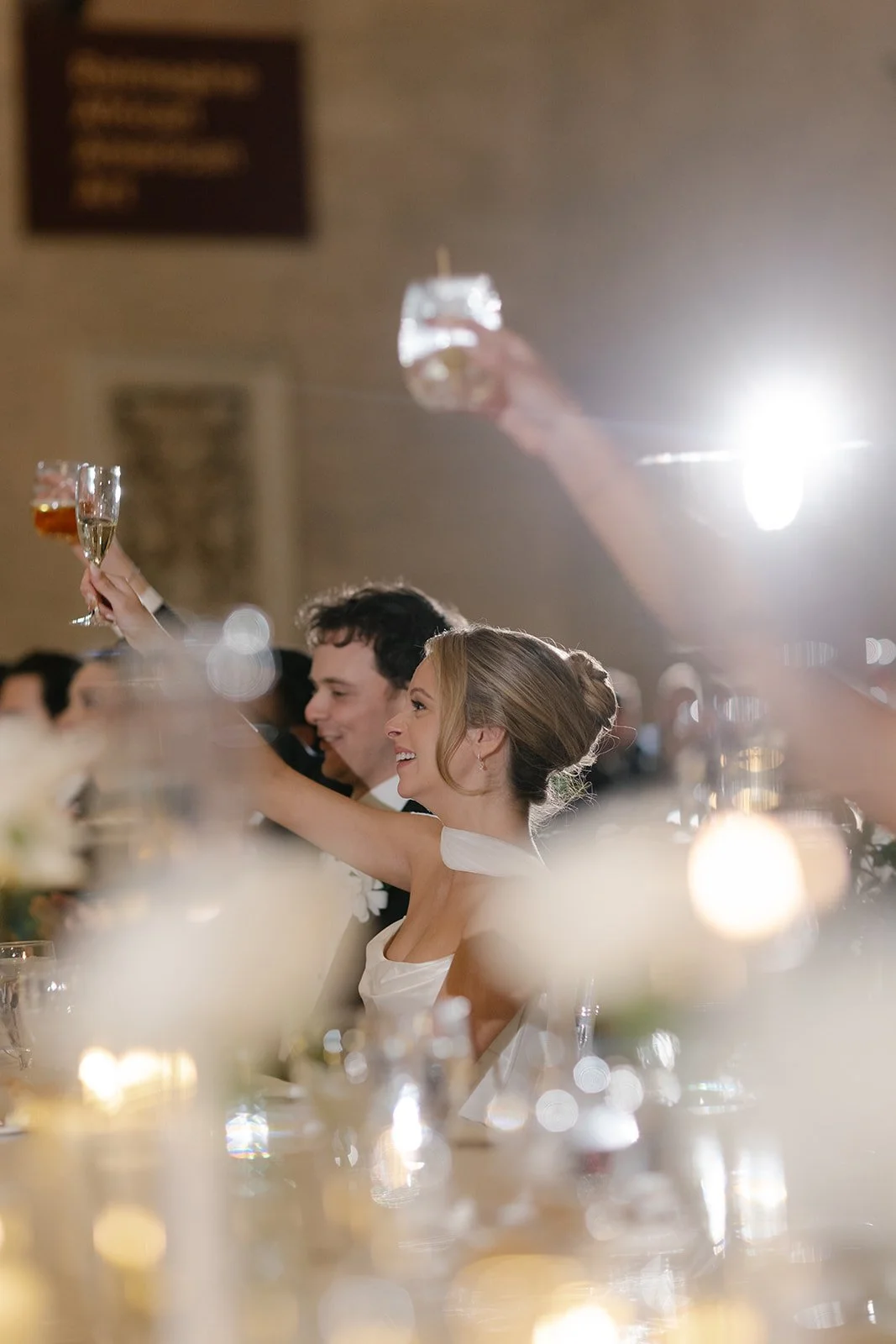 Bride and wedding guests raising champagne glasses during a reception toast