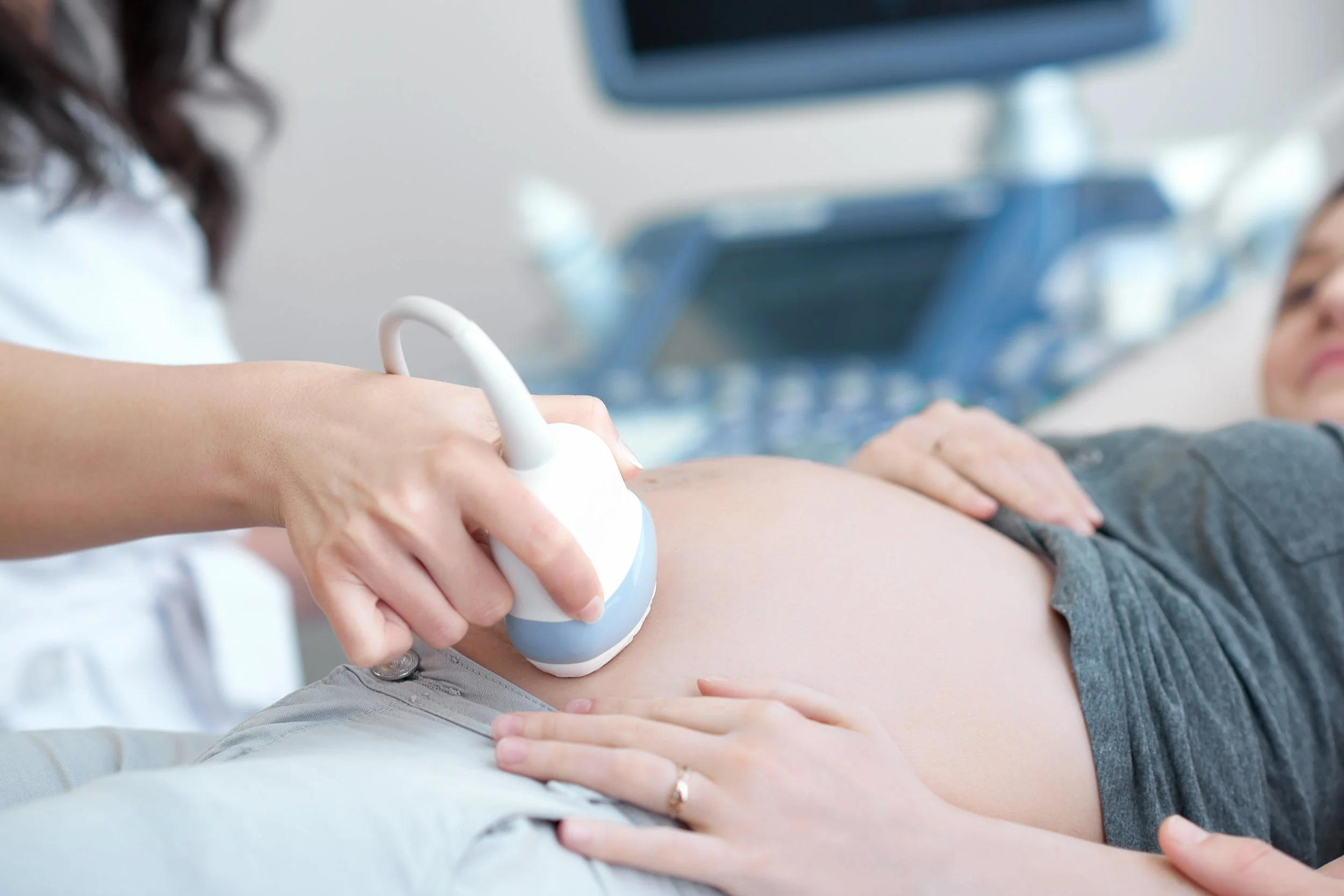 A healthcare professional is performing an ultrasound scan on a person's abdomen in a clinical setting.