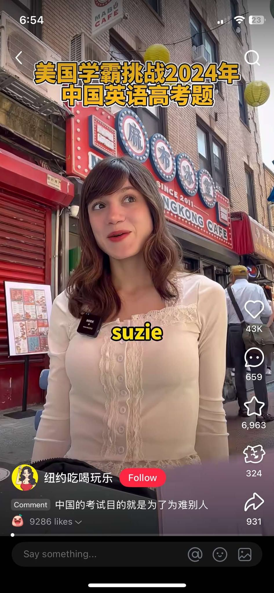 A woman named Suzie standing on a city street in front of a red storefront with Asian signage, yellow paper lanterns hanging above, and a menu board on the side.