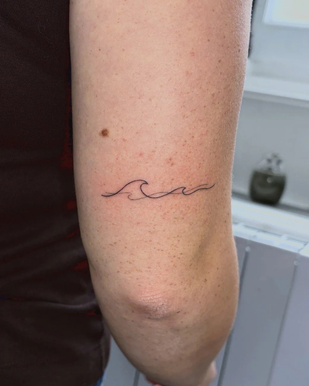 Vague fine line tatouée sur le bras, par Finime à Lyon