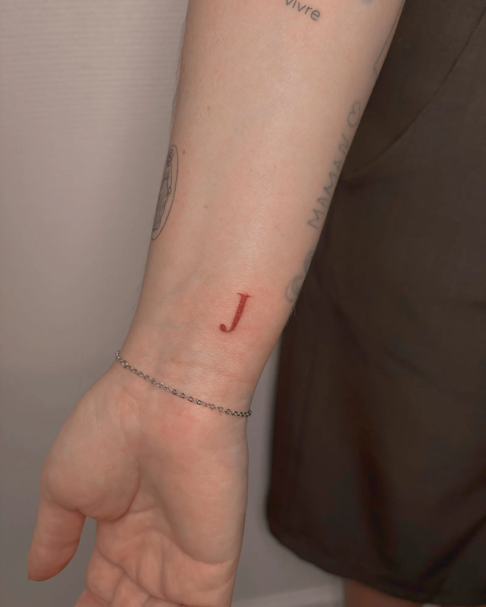 Tatouage d'une initiale J en rouge sur le poignet, réalisé par Finime à Lyon