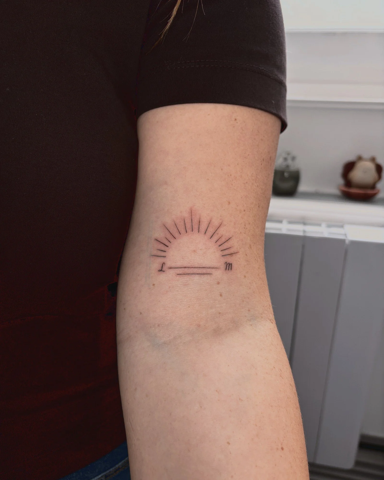 Tatouage fine line d'un soleil levant sur le bras, réalisé par Finime à Lyon