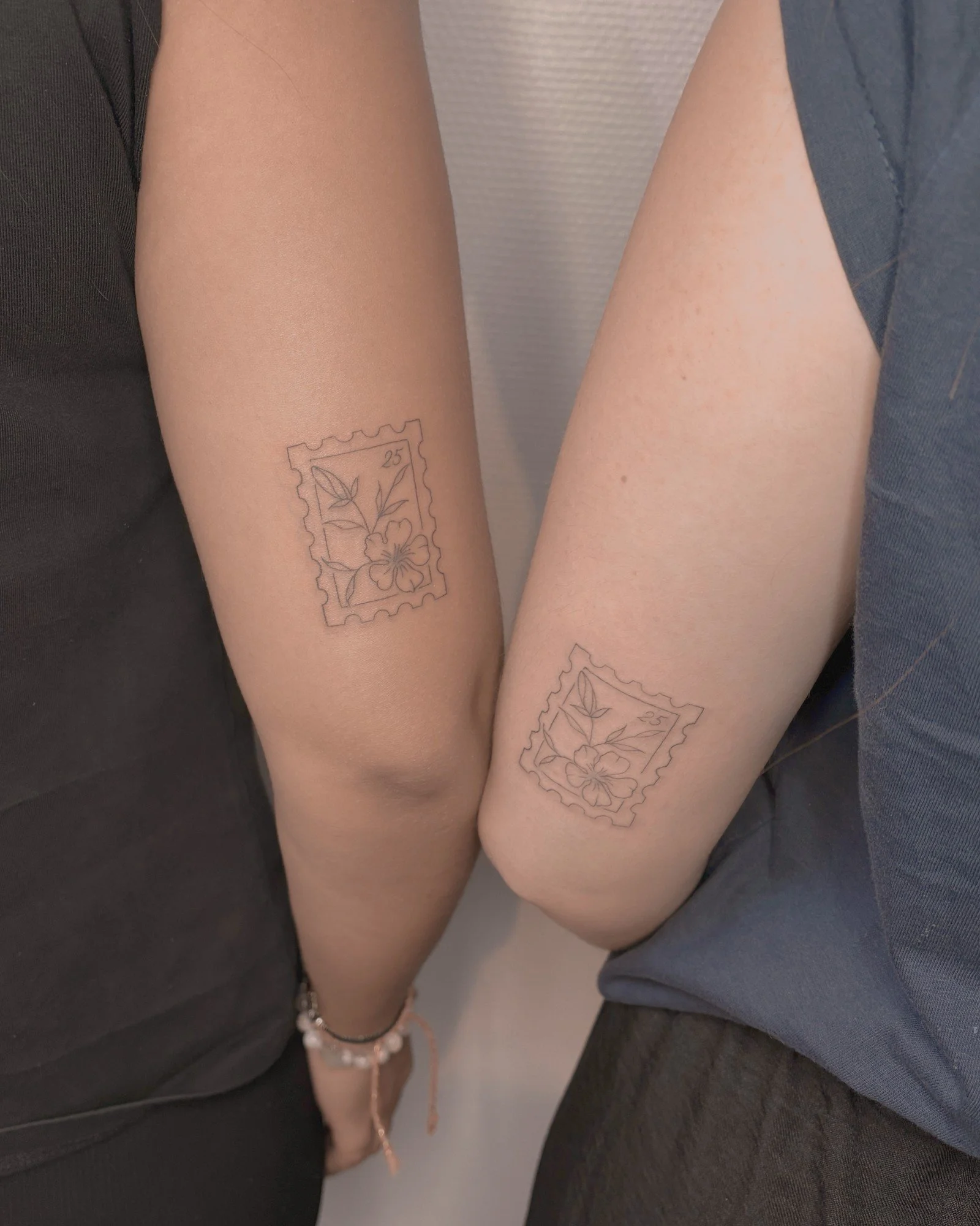 Tatouages fine line assortis en forme de timbres, réalisés par Finime à Lyon