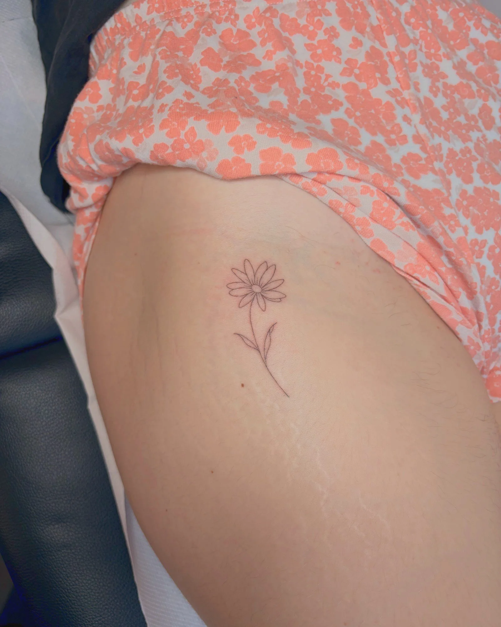 Tatouage fine line d'une marguerite sur la cuisse, réalisé par Finime à Lyon