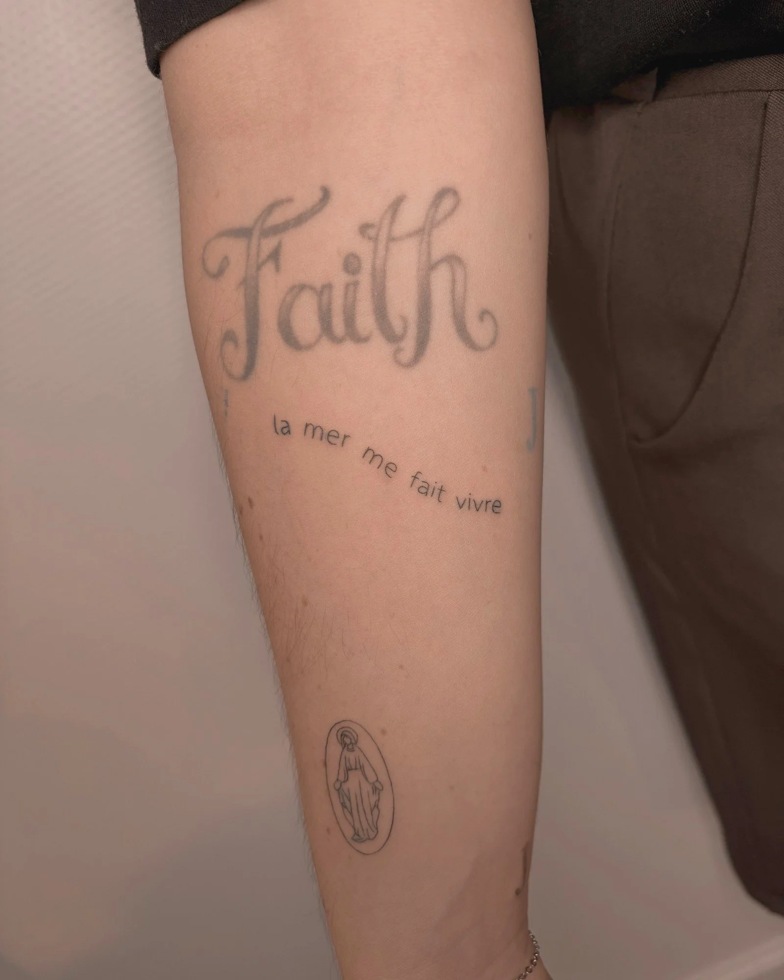 Tatouage fine line d'un lettrage « la mer me fait vivre » sur l'avant-bras, réalisé par Finime à Lyon