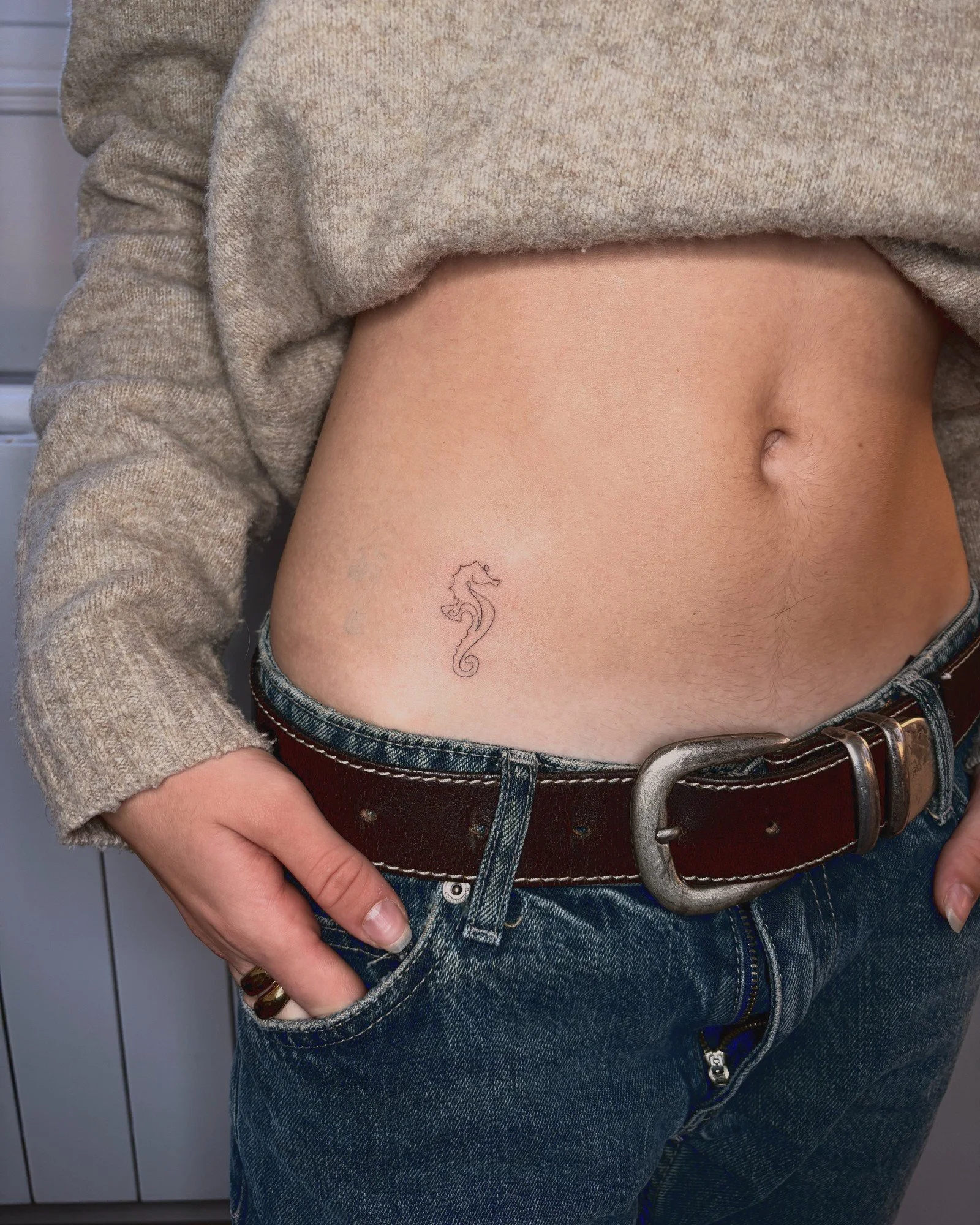 Tatouage fine line d'un hippocampe sur le ventre, réalisé par Finime à Lyon