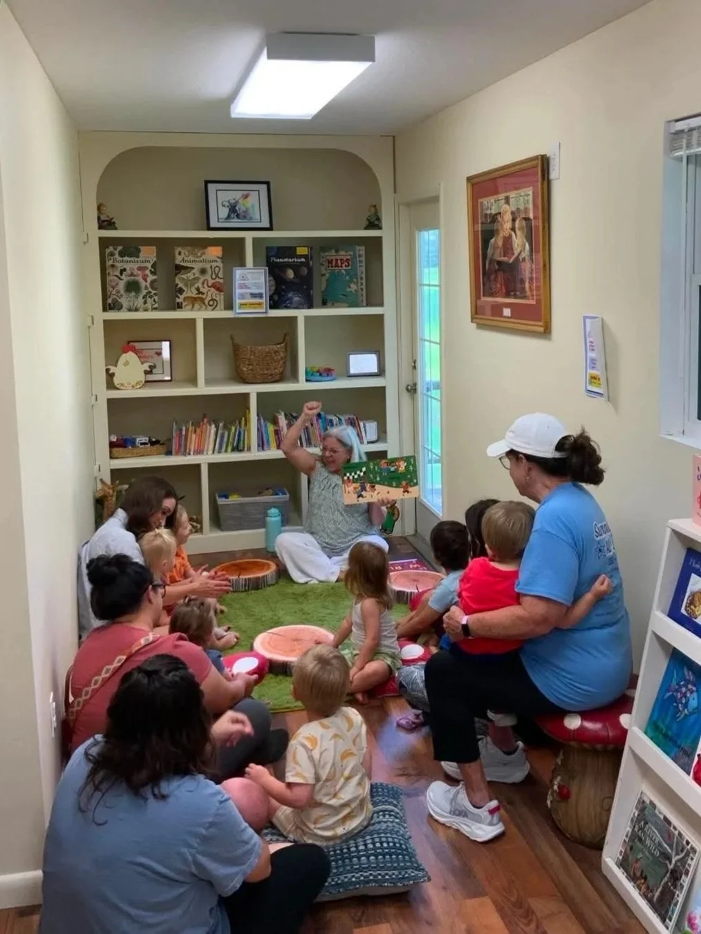 Adults and young children gather for a storytime activity in a cozy library reading room.
