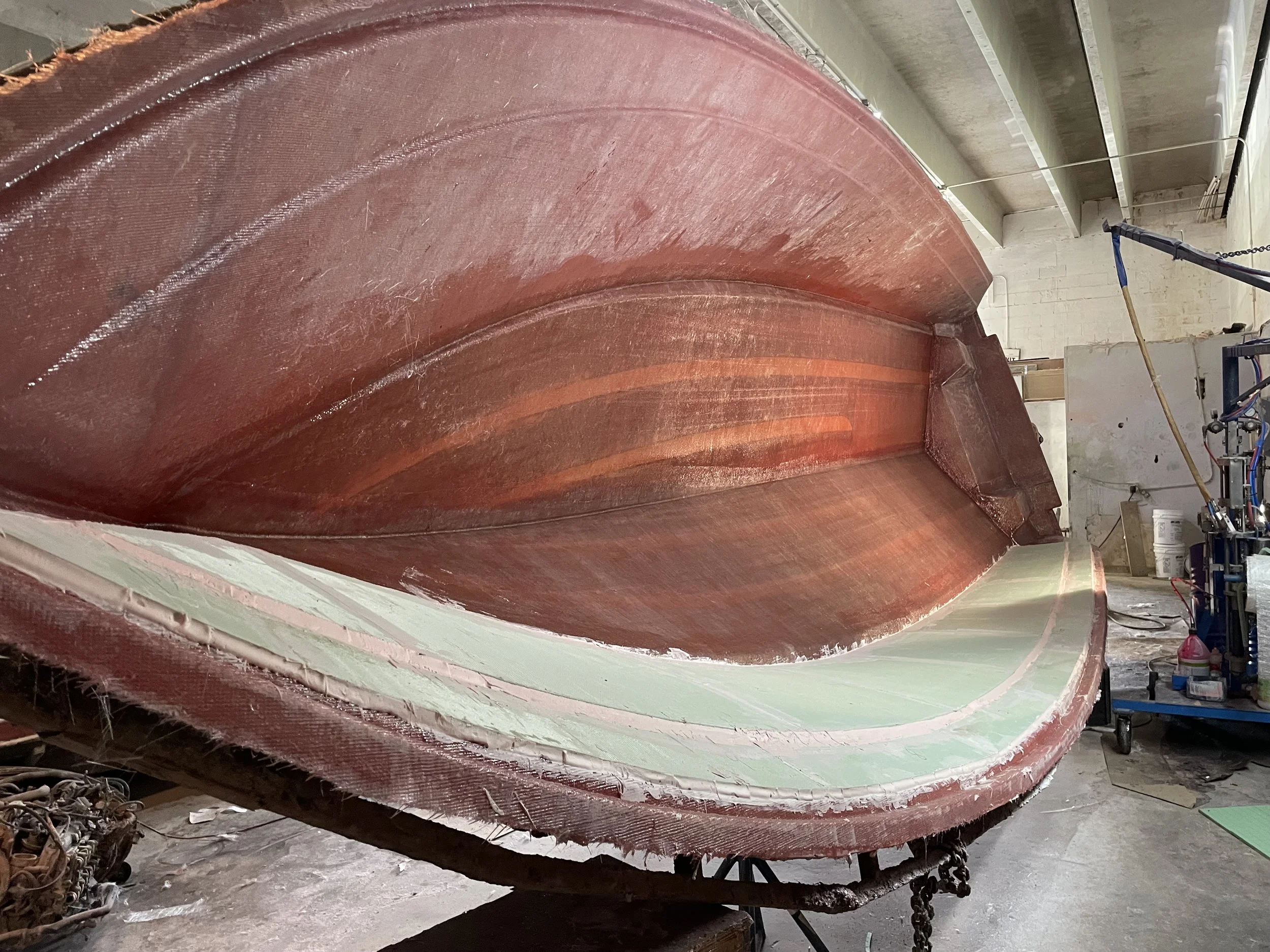 Resin Application: Resin is worked through the fiberglass fabric with attention to consistent saturation throughout the laminate.

Laminate Consolidation: Each fiberglass layer is carefully rolled to remove trapped air and bring the layers into close