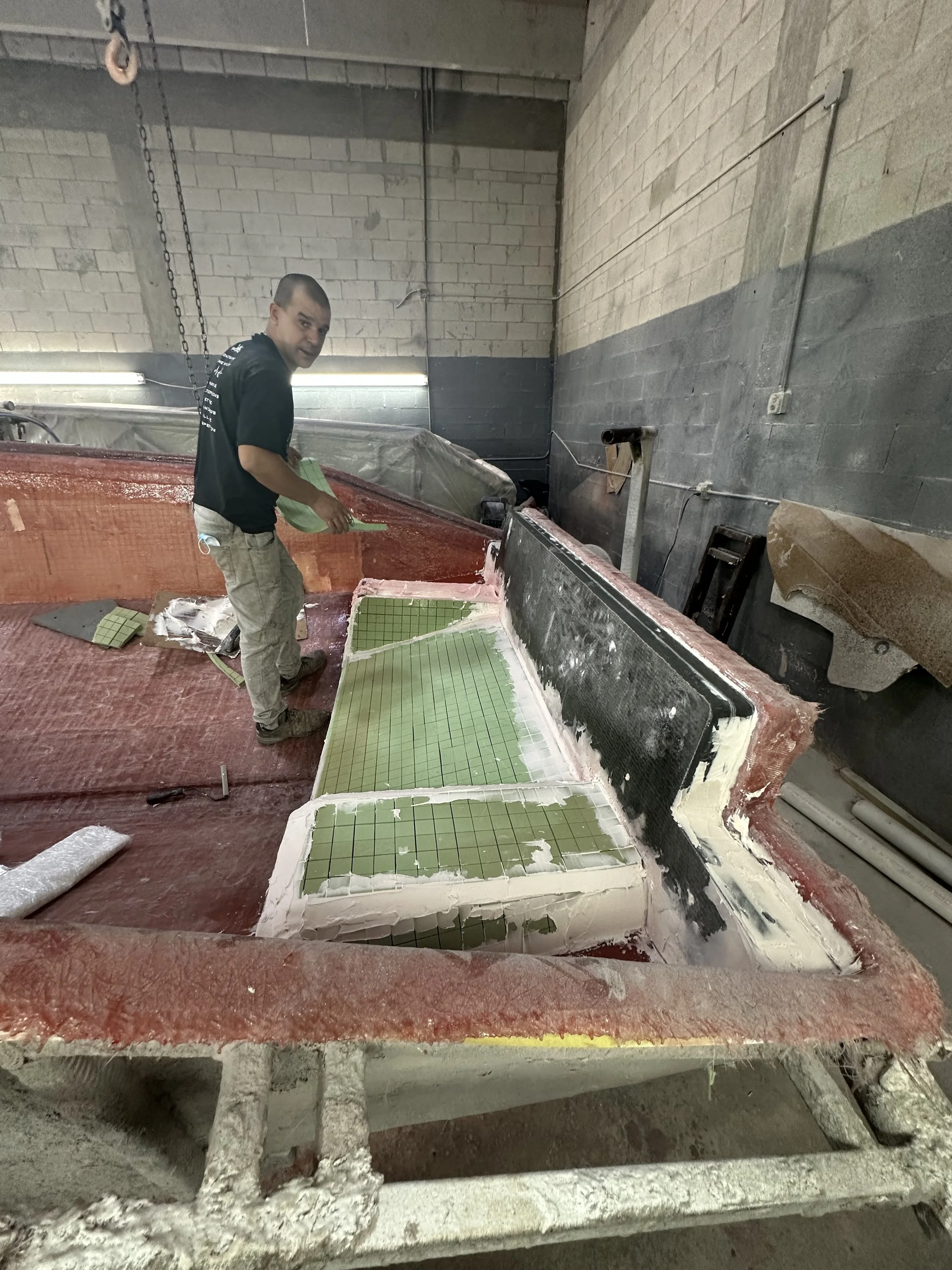 Resin Application: Resin is worked through the fiberglass fabric with attention to consistent saturation throughout the laminate.

Laminate Consolidation: Each fiberglass layer is carefully rolled to remove trapped air and bring the layers into close