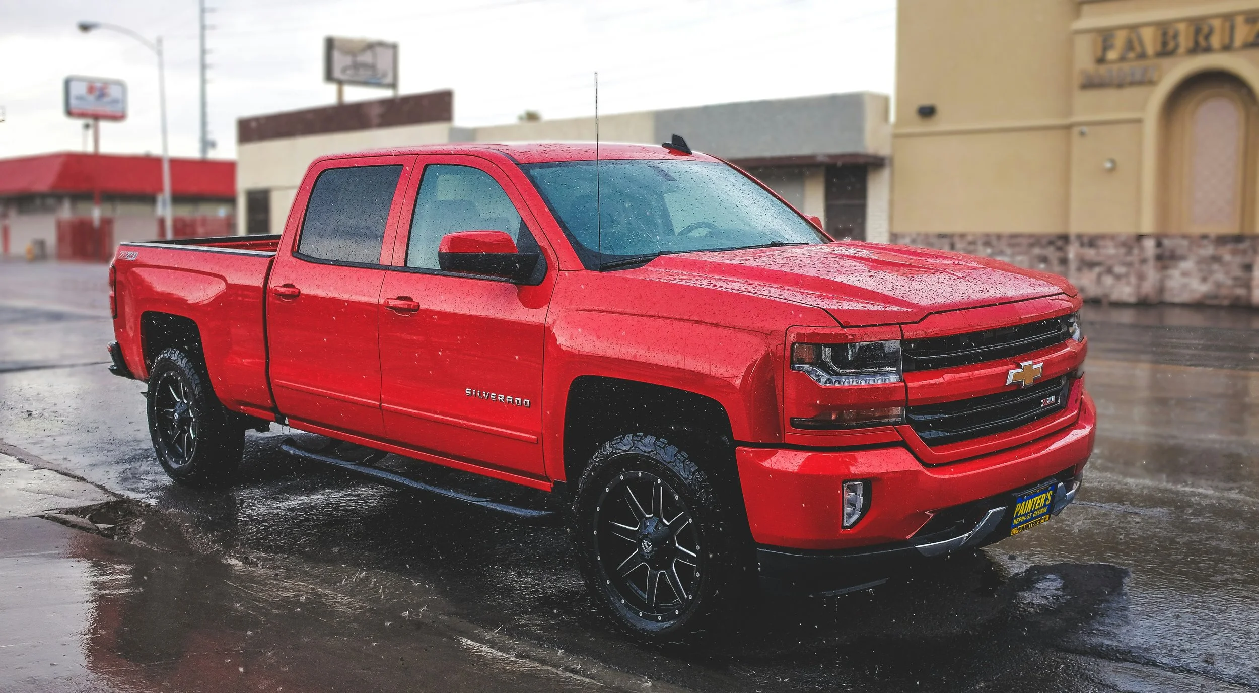 Red Chevrolet Silverado pickup truck parked on a rainy day.