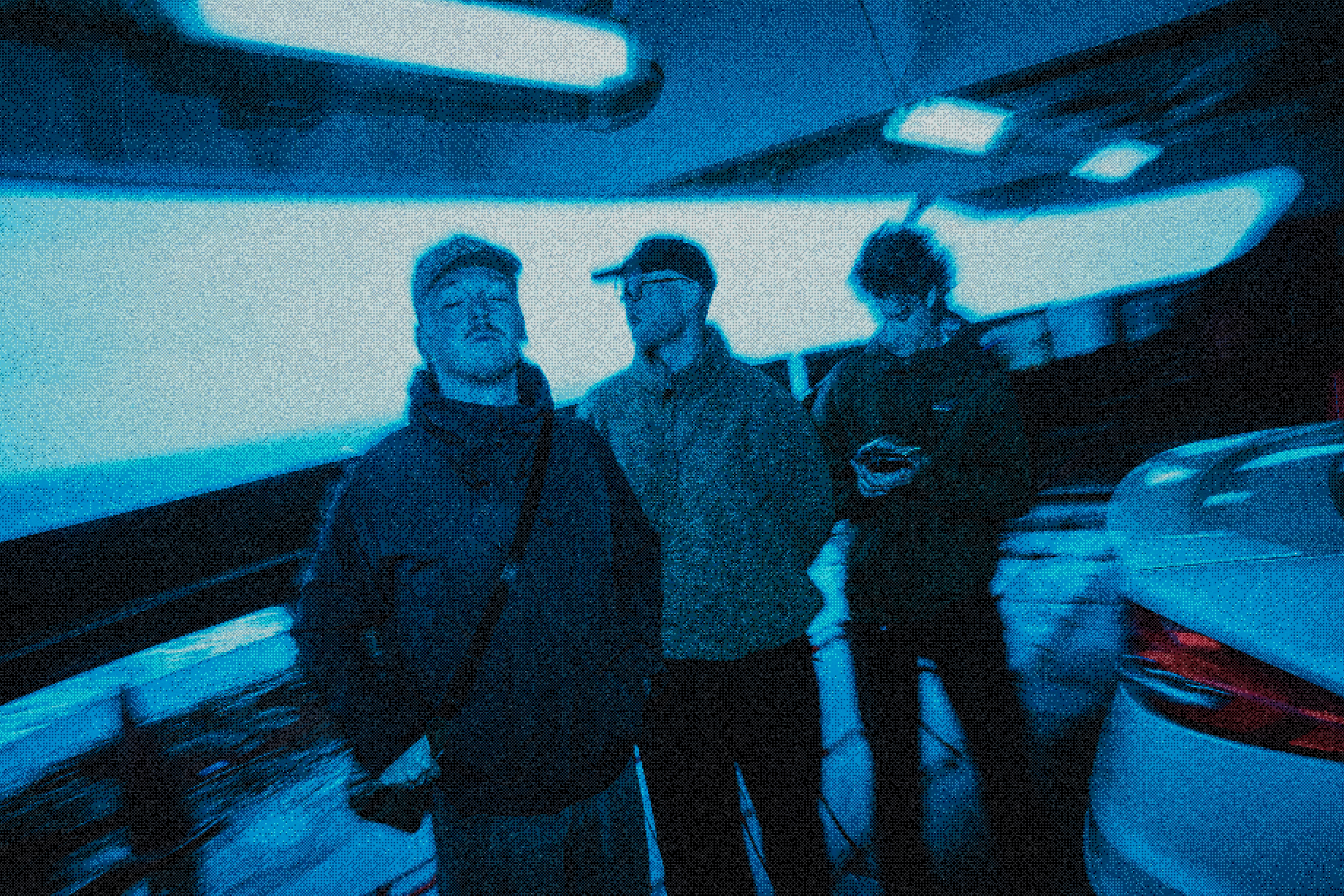 Three friends standing outdoors at night, drinking from cans, with no visible background details.