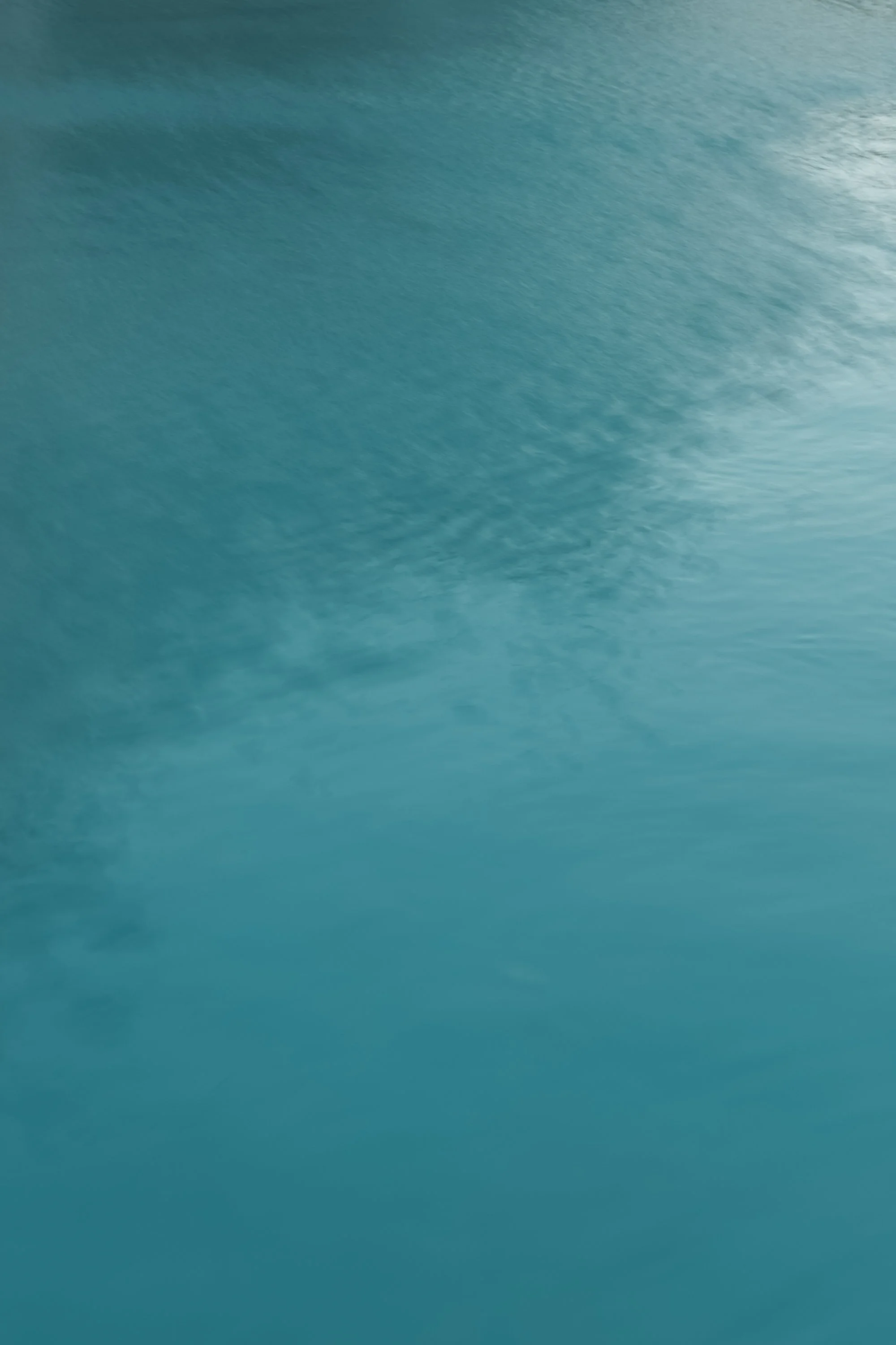 Close-up of a textured blue-green surface with a subtle gradient and soft, wispy patterns.
