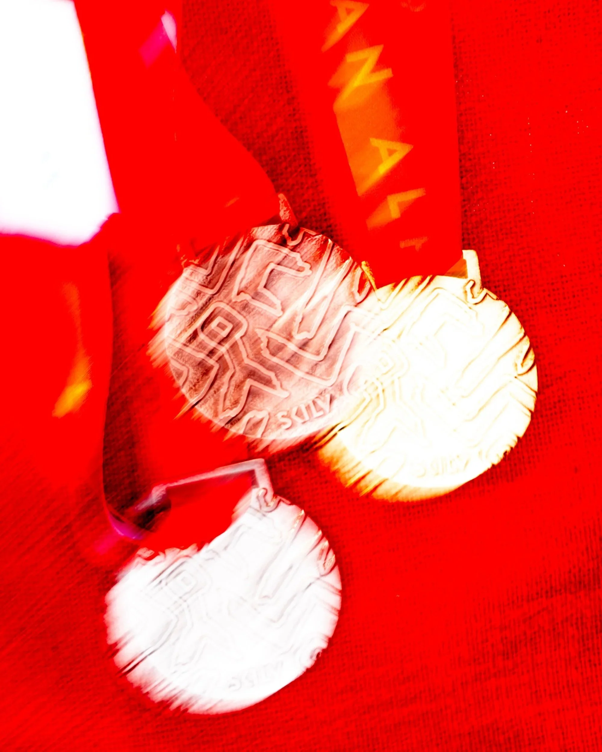 A red Santa hat with white fur trim lies on a red textured surface, partially covered by a red box with yellow text.