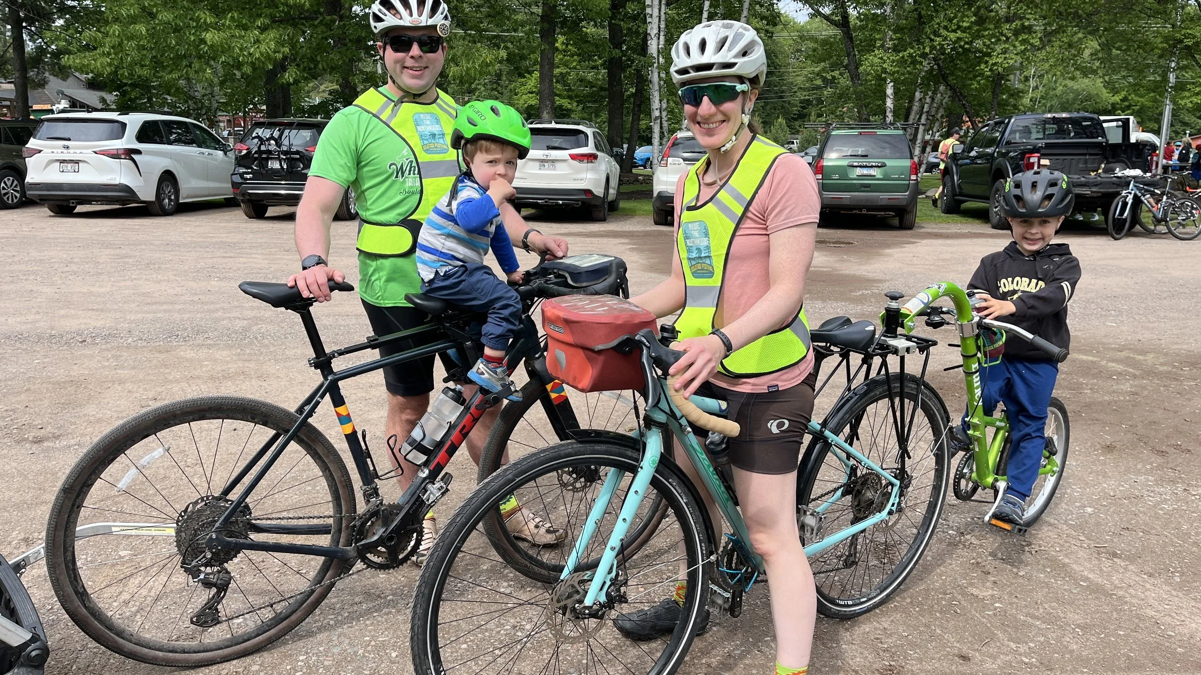 Family wearing bicycle helmets and reflective vests with children on bikes outdoors