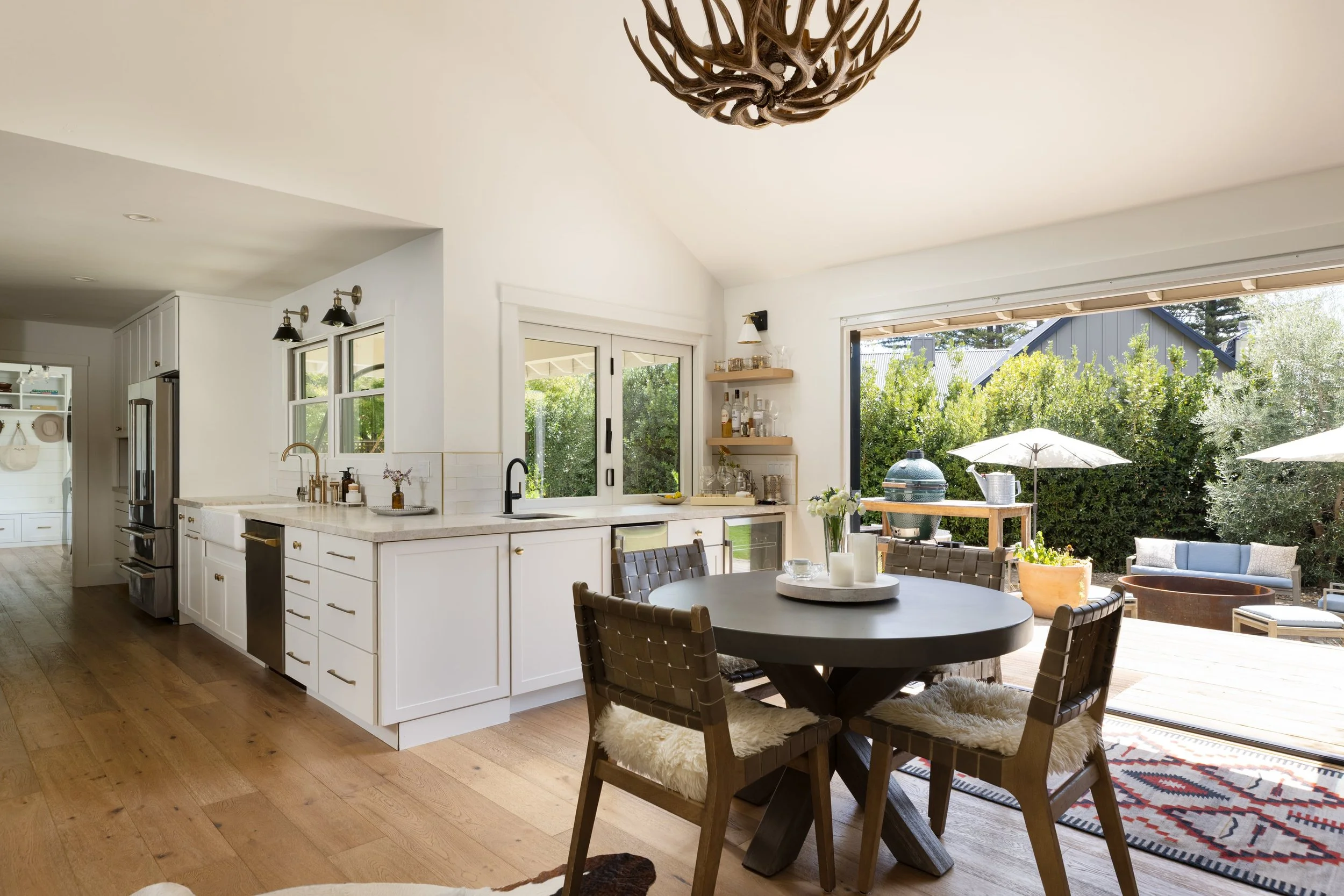 Open-concept kitchen and dining area with large sliding glass doors leading to outdoor patio with patio furniture and greenery