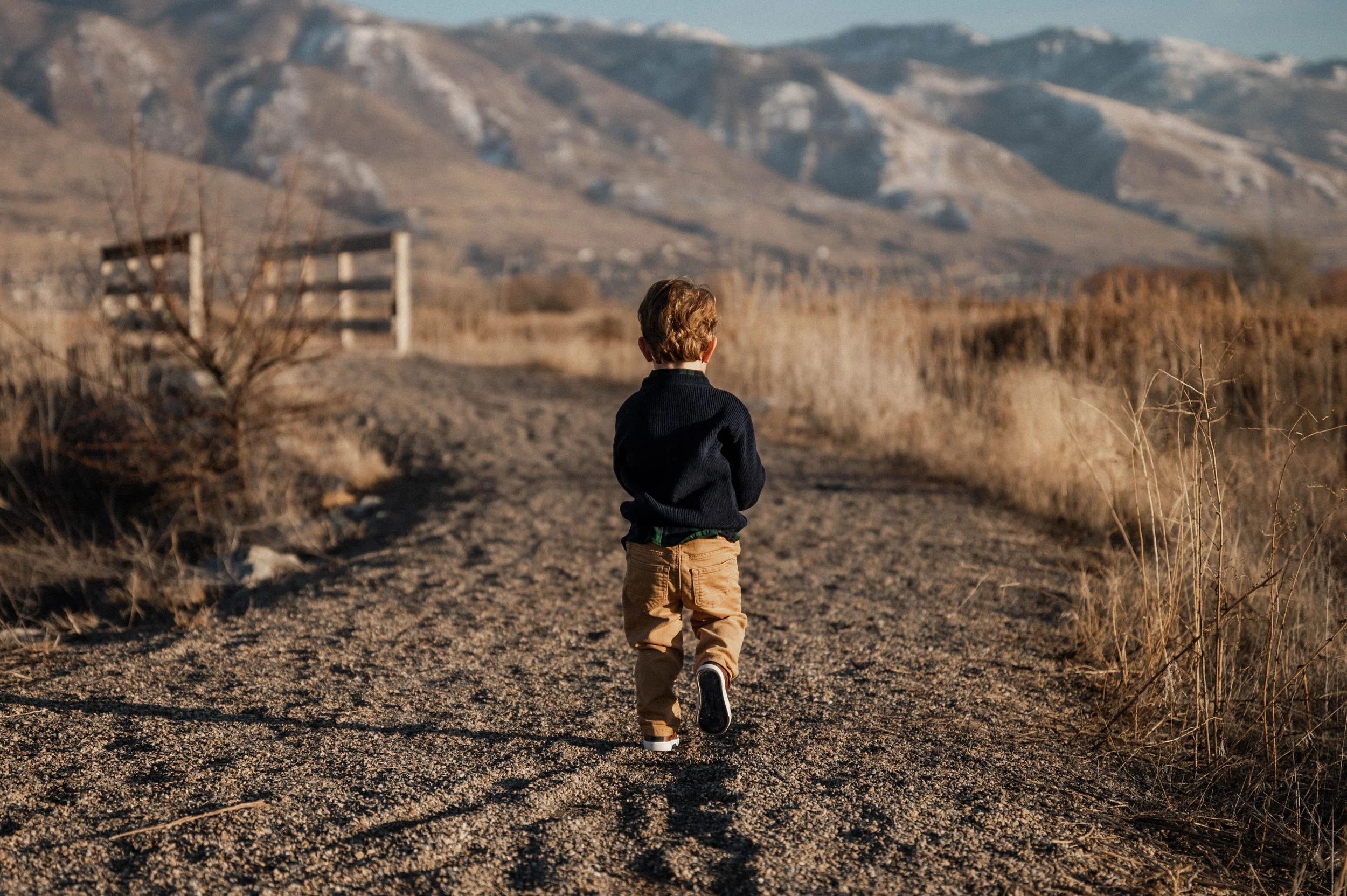 A little boy walking down a mountain trail