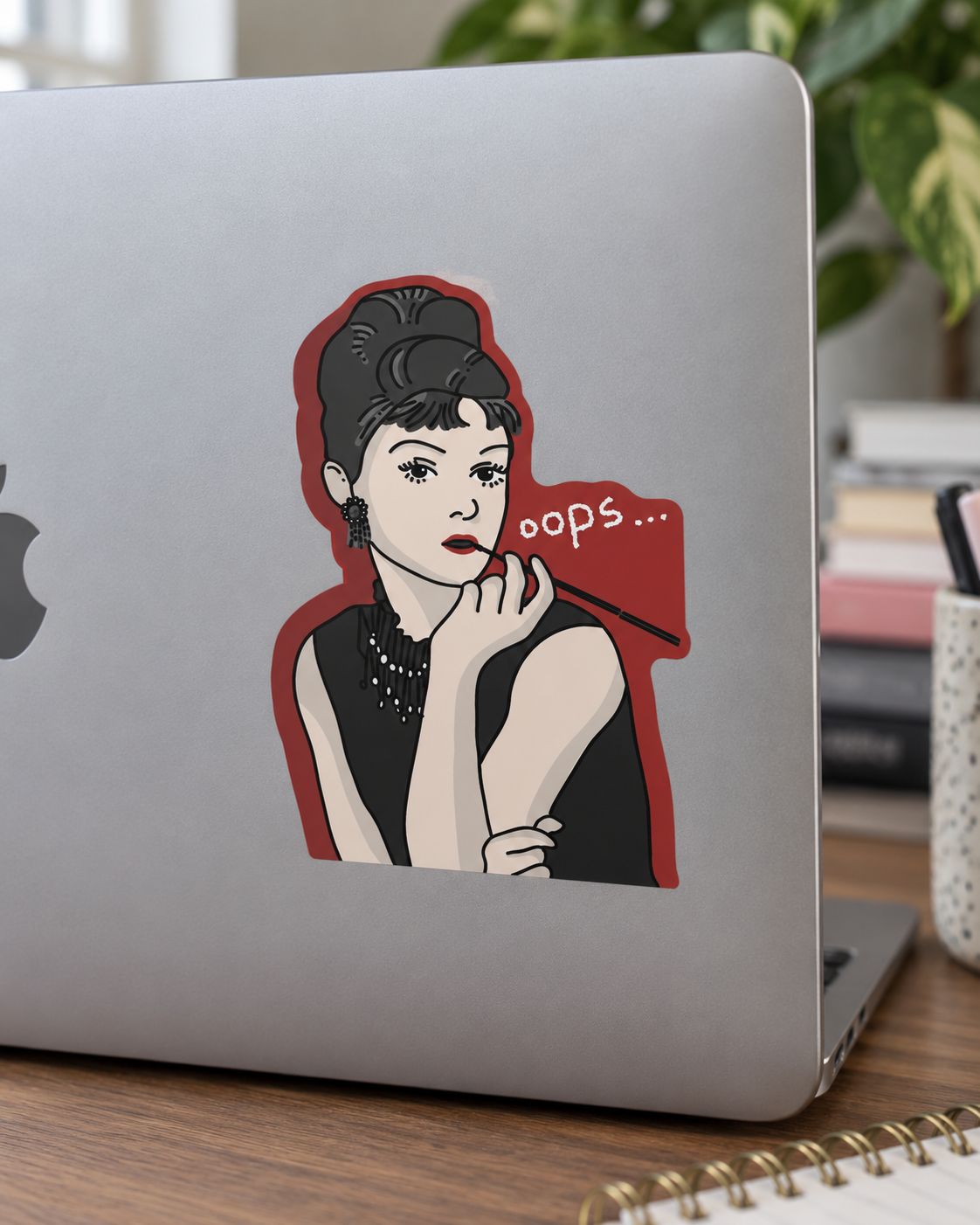 Silver laptop with a vintage-style woman applying lipstick sticker and “OOPS...” text