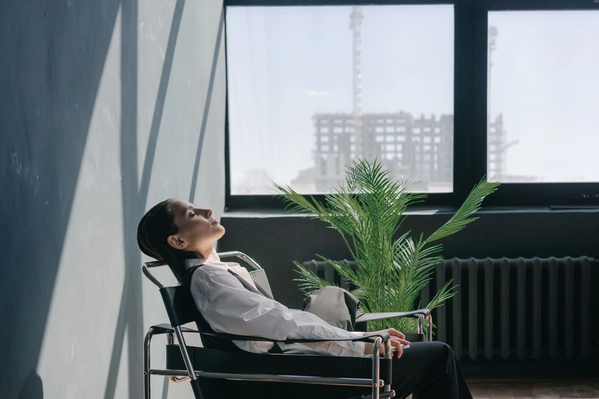 person sitting quietly in a chair by a window, eyes closed