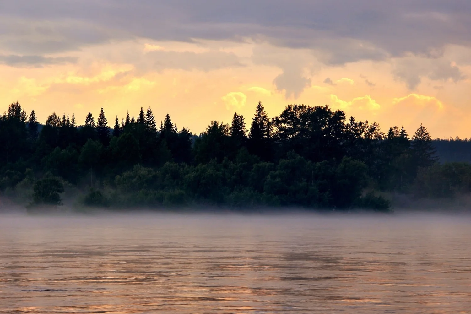 Mist rising from a river at dusk.