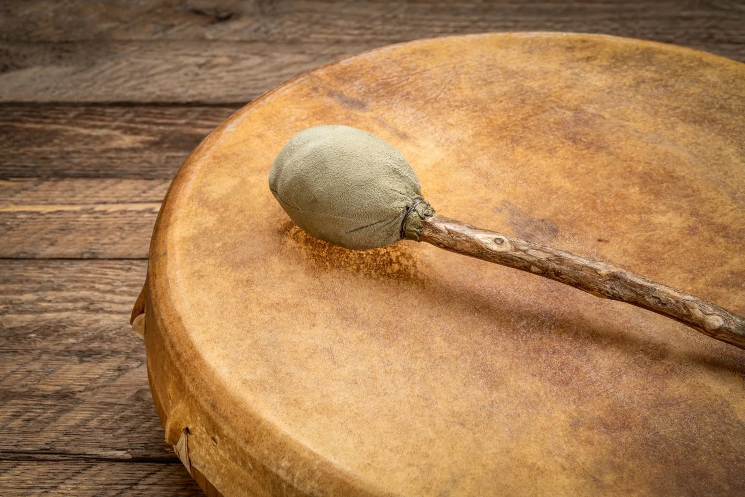 A frame drum and a rattle resting side by side.