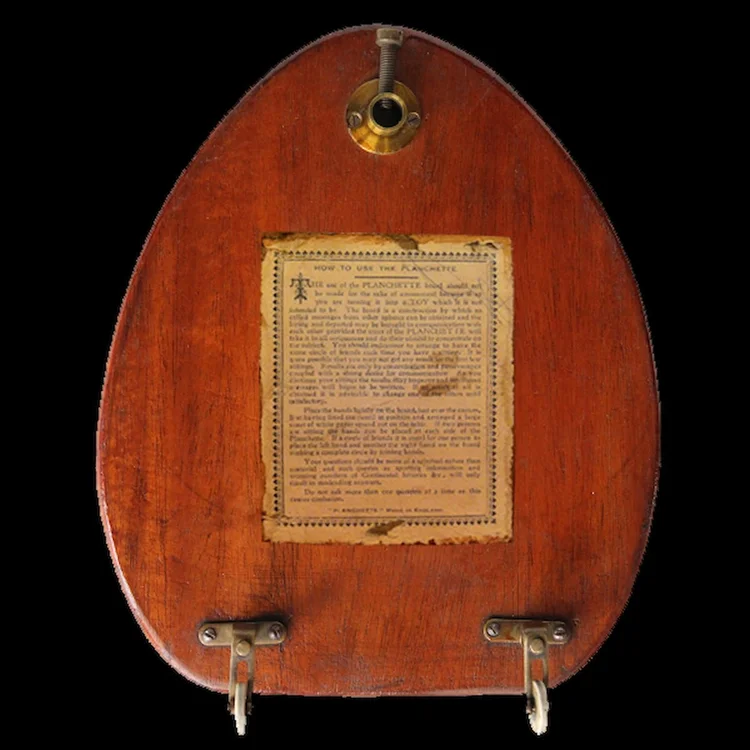 A historic wooden planchette photographed from above against a dark background.
