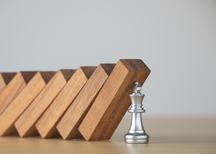 Chess queen piece in front of a row of wooden dominoes.