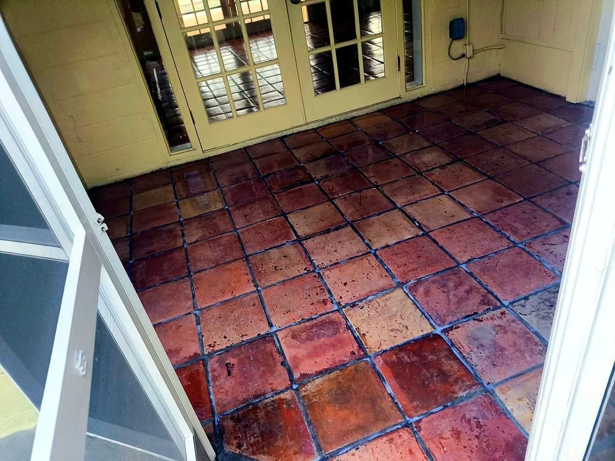 Enclosed porch with terracotta tile flooring, cream walls, and glass-paneled double doors