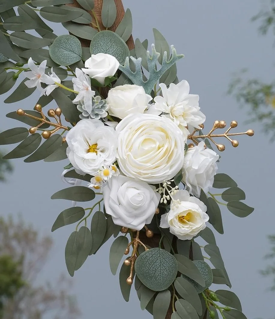 Close-up of a bridal bouquet with white roses, daisies, greenery, and gold accents.